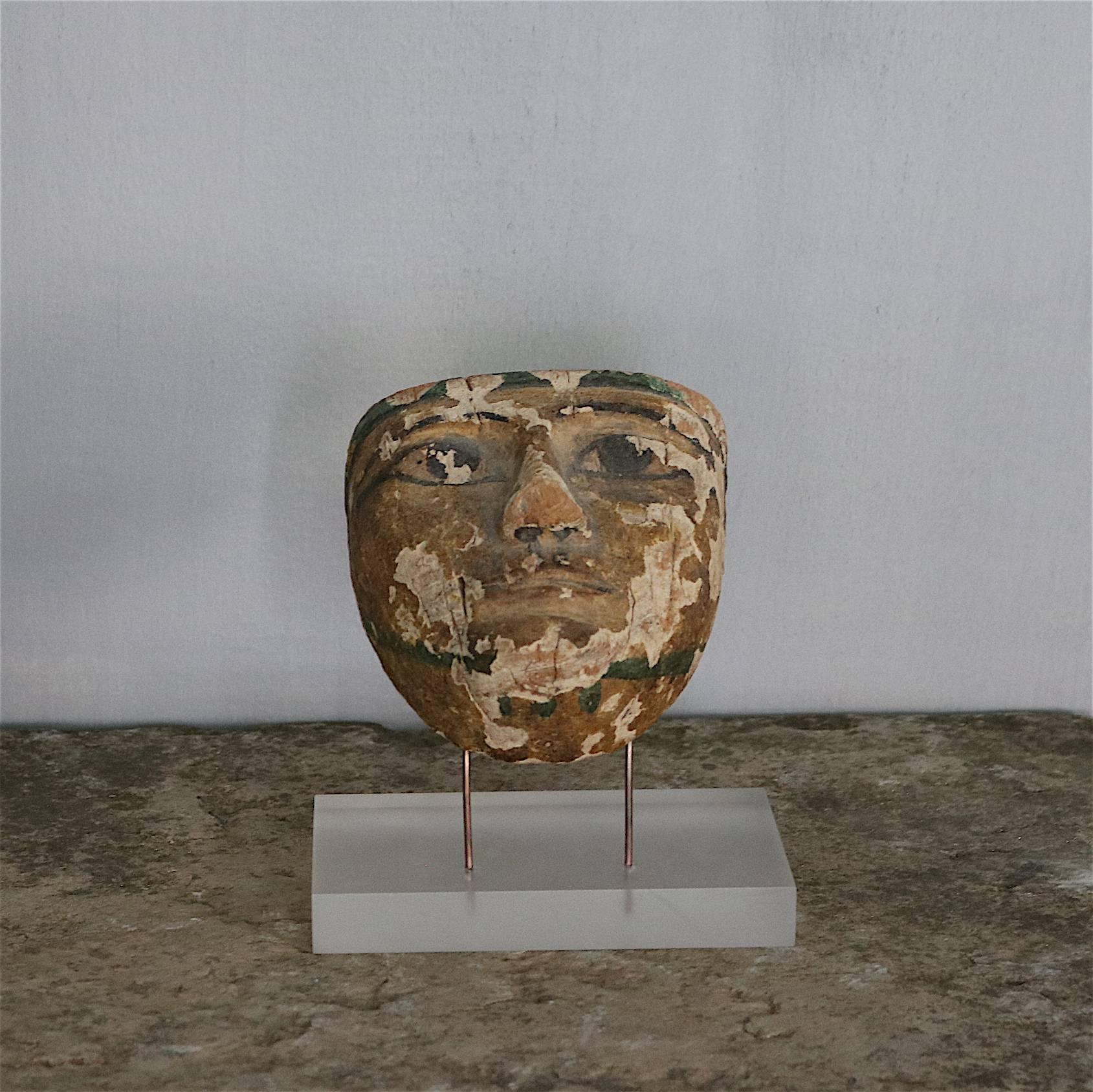 Ancient mummy mask in carved wood from the 21st-22nd dynasty. Paint of green, yellow and black. Mounted on perspex.