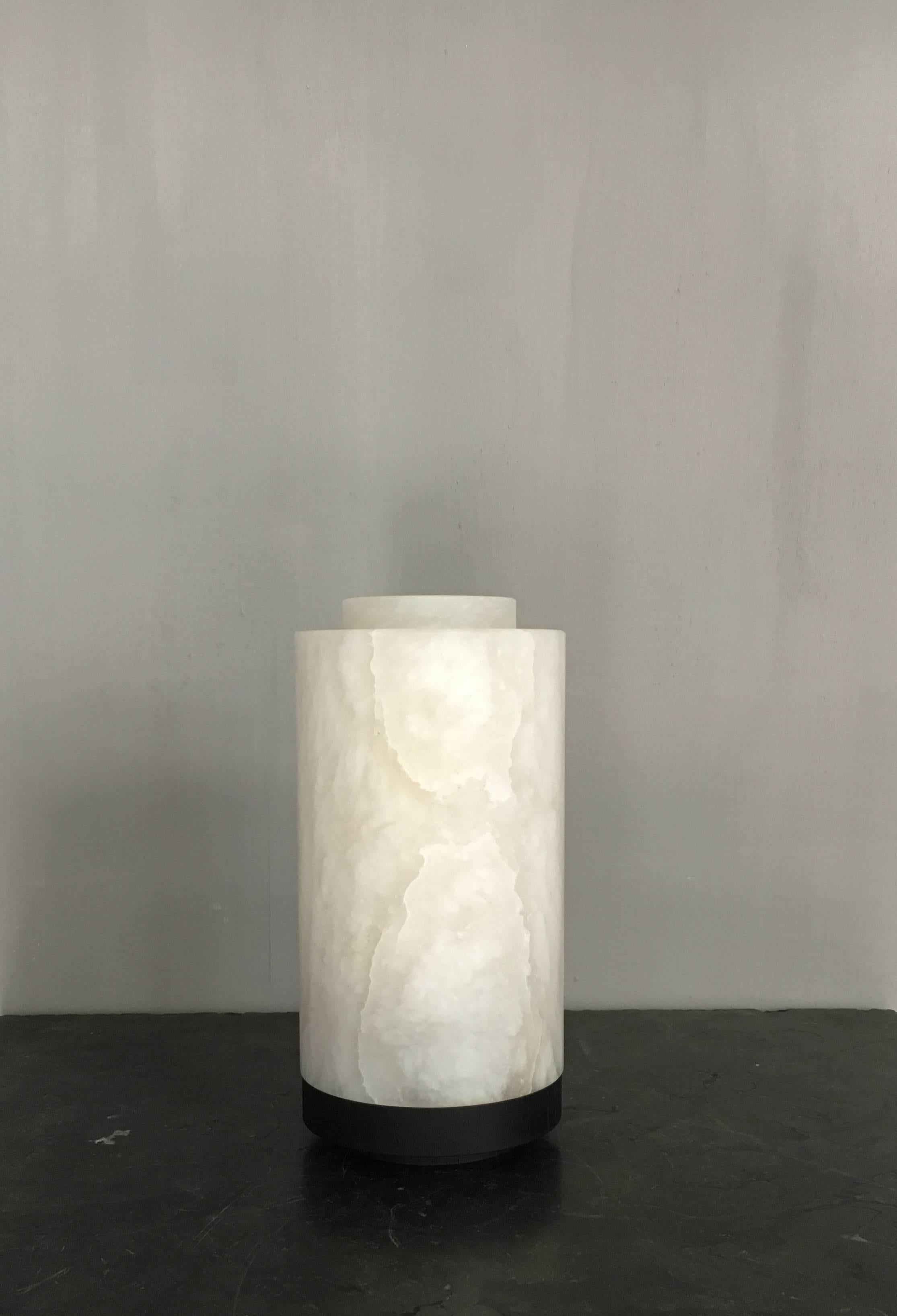 Beautiful lamp in alabaster from Michaël Verheyden with removable top and base in black stained solid oak. The lamp has a warm soft glow.
Made with an old school plug, switch and twisted cable.
 
