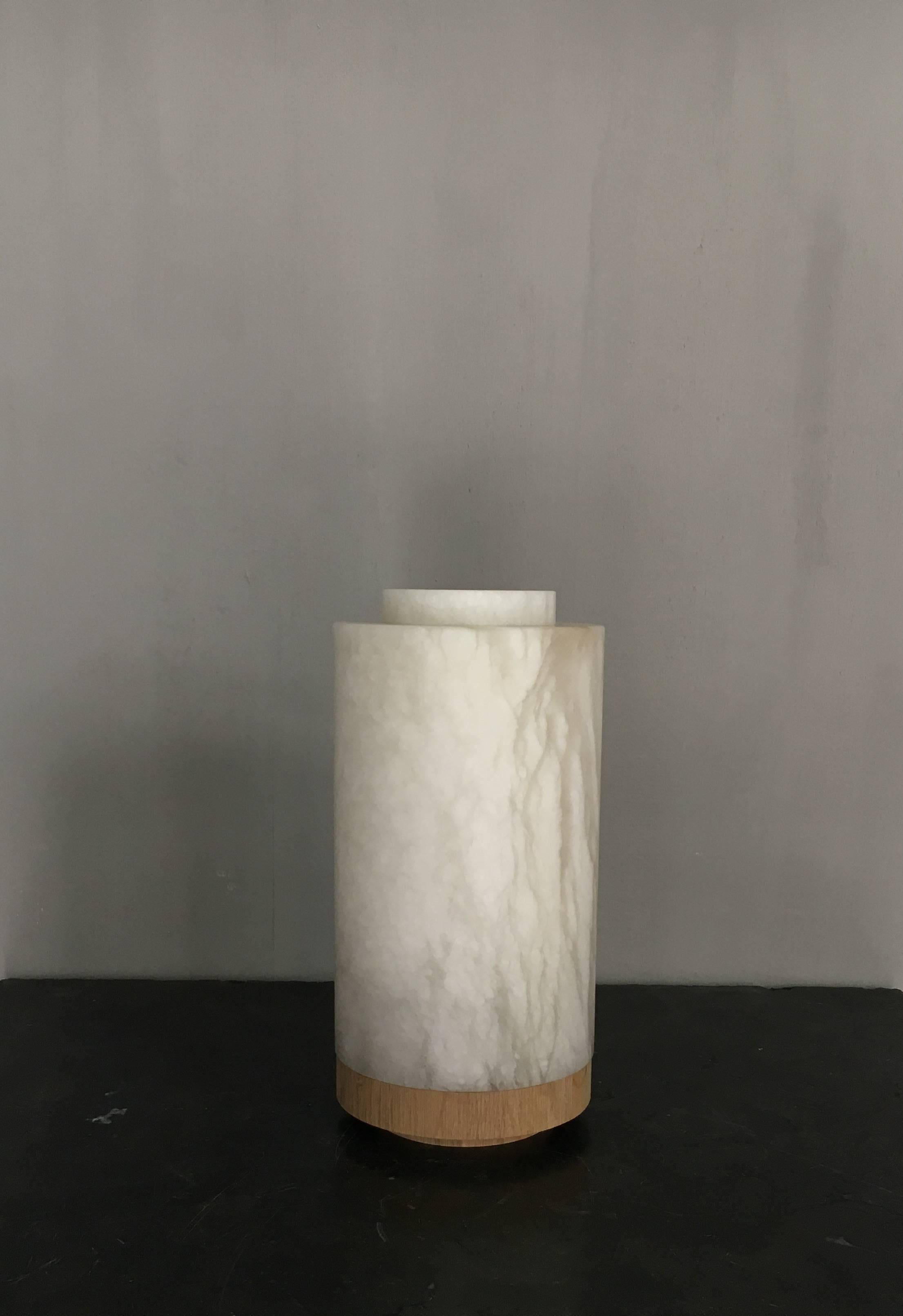 Beautiful lamp in alabaster from Michaël Verheyden with removable top and base in natural solid oak. The lamp has a warm soft glow.
Made with an old school plug, switch and twisted cable.
 