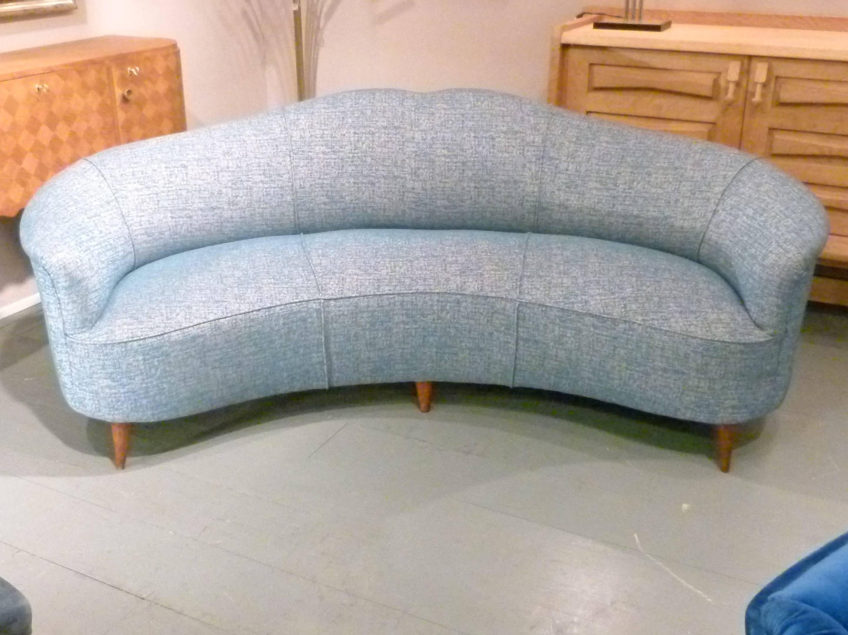 Curved sofa with flared armrests standing on six conical woo feet. Covered with a new blue on grey background fabric.
1950s-1960s Italian work.
This sofa has been entirely reupholstered and covered with a new fabric. 
Perfect condition.