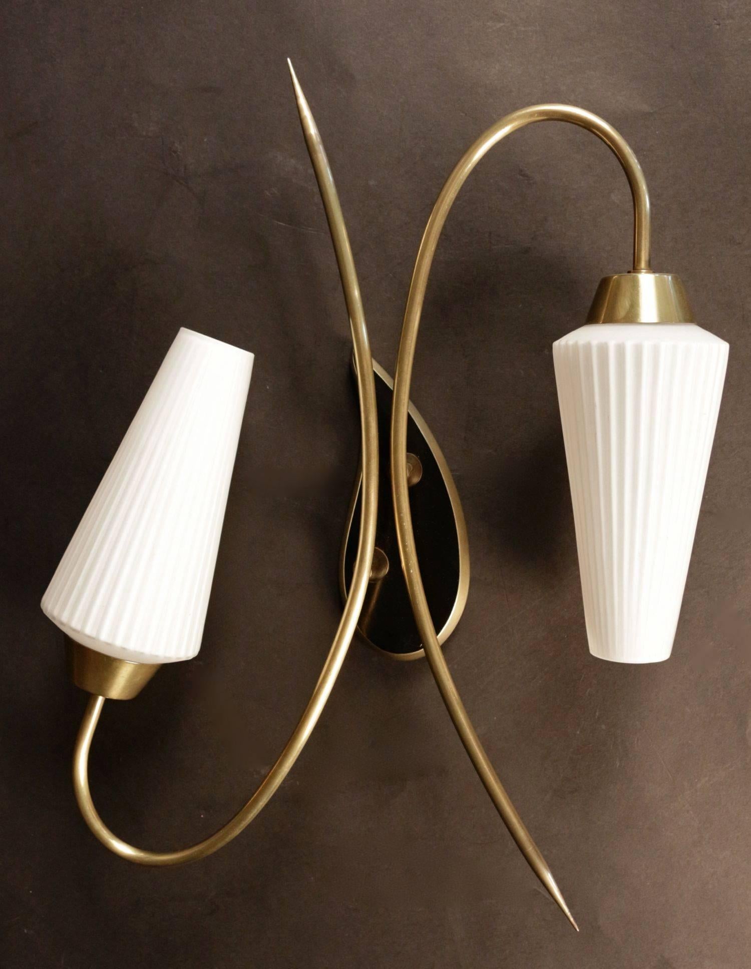 Two 1950s brass sconces with white opaline glass. One is composed of three brass arms ending with three folded opaline glass lampshades and the other is composed of two brass arms ending with two folded opaline glass lampshades. For both sconces the