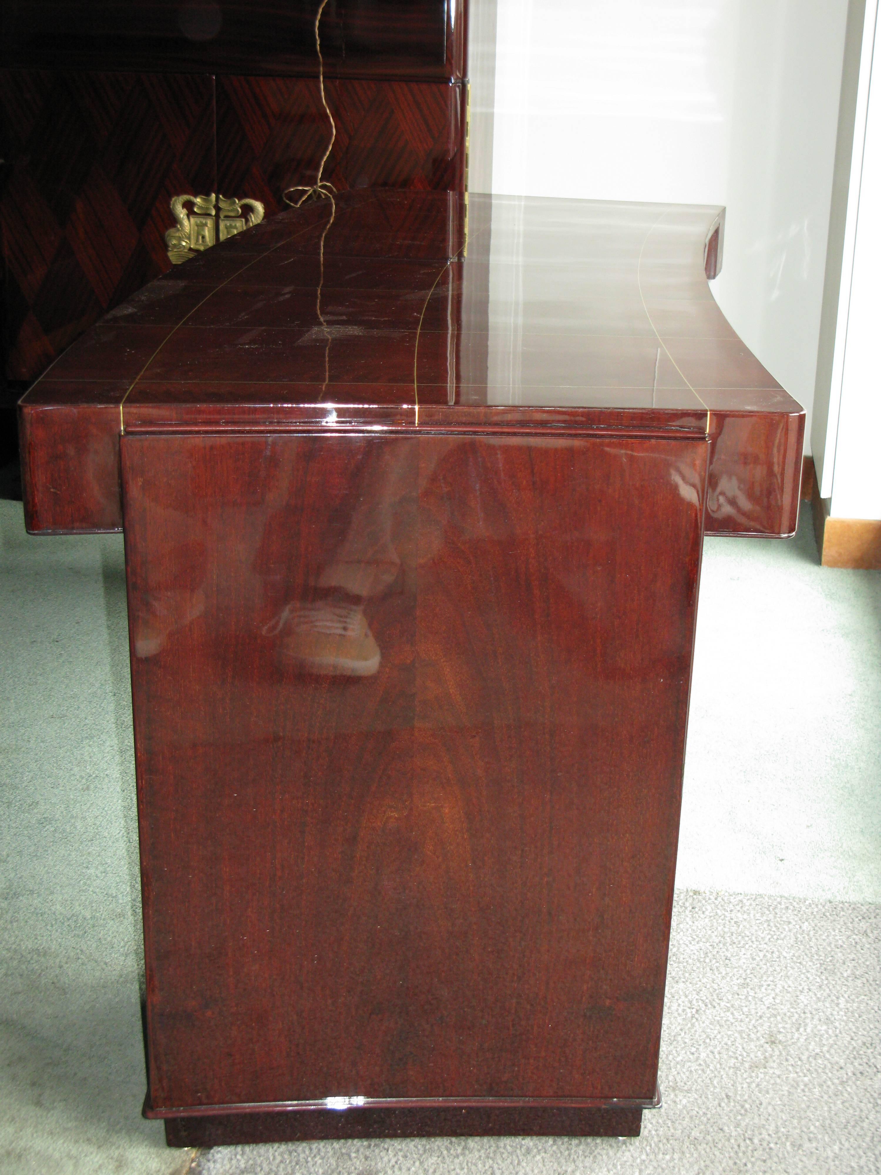 Desk in Rio rosewood with brass filets inlaids on top.
Top slightly curved and both sides are concave.
There are two drawers in the belt and two side blocks opening with a door, showing oak shelves on both sides.
Art Deco French work, circa 1935