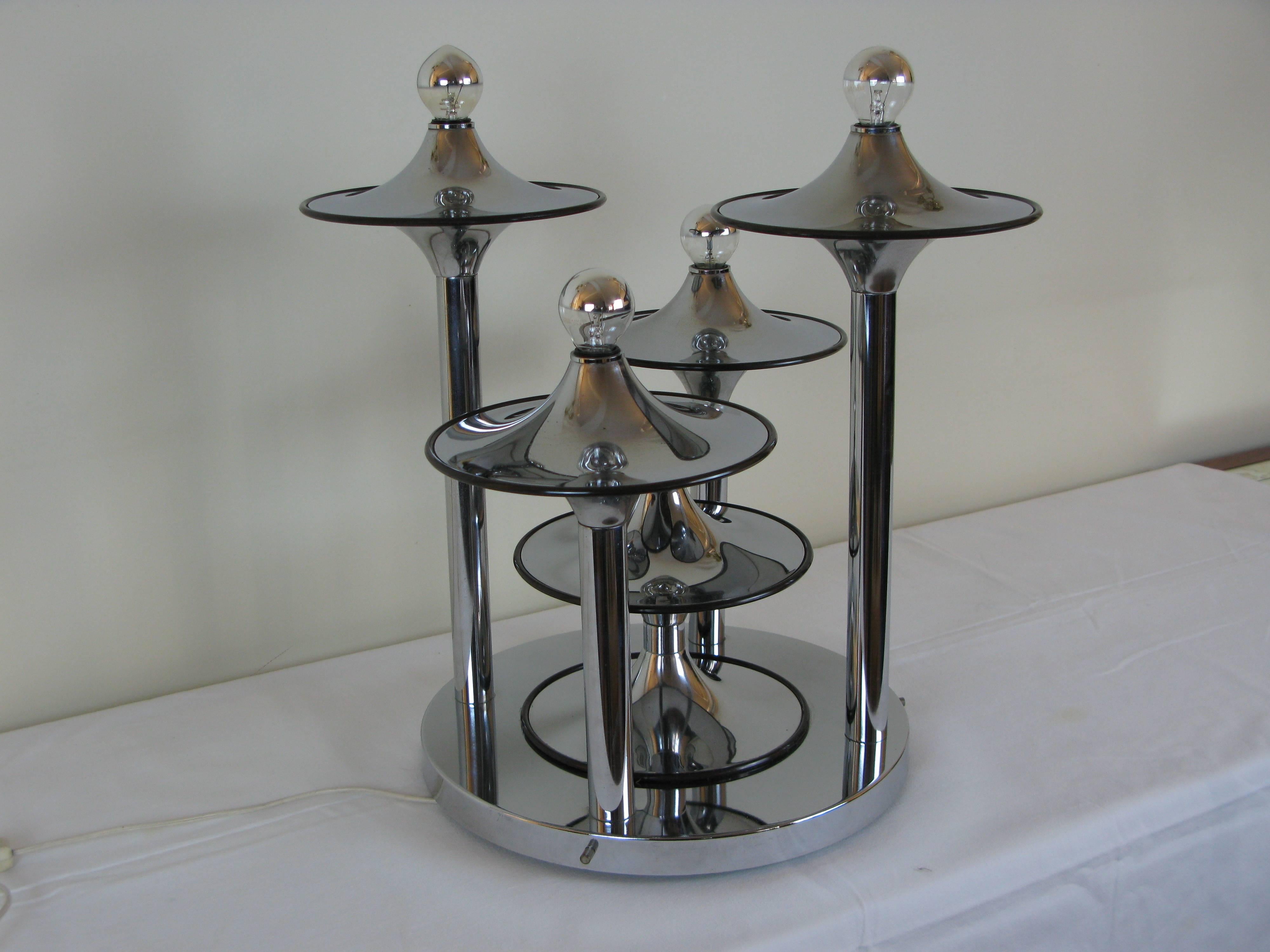 Italian table lamp in chrome metal consisting of circular base on which are fixed five lighted arms. Chrome metal disks forming flying soccer are surmounting the arms. 
1960s, Italian work attributed to Stilnovo.
Very good original condition.
