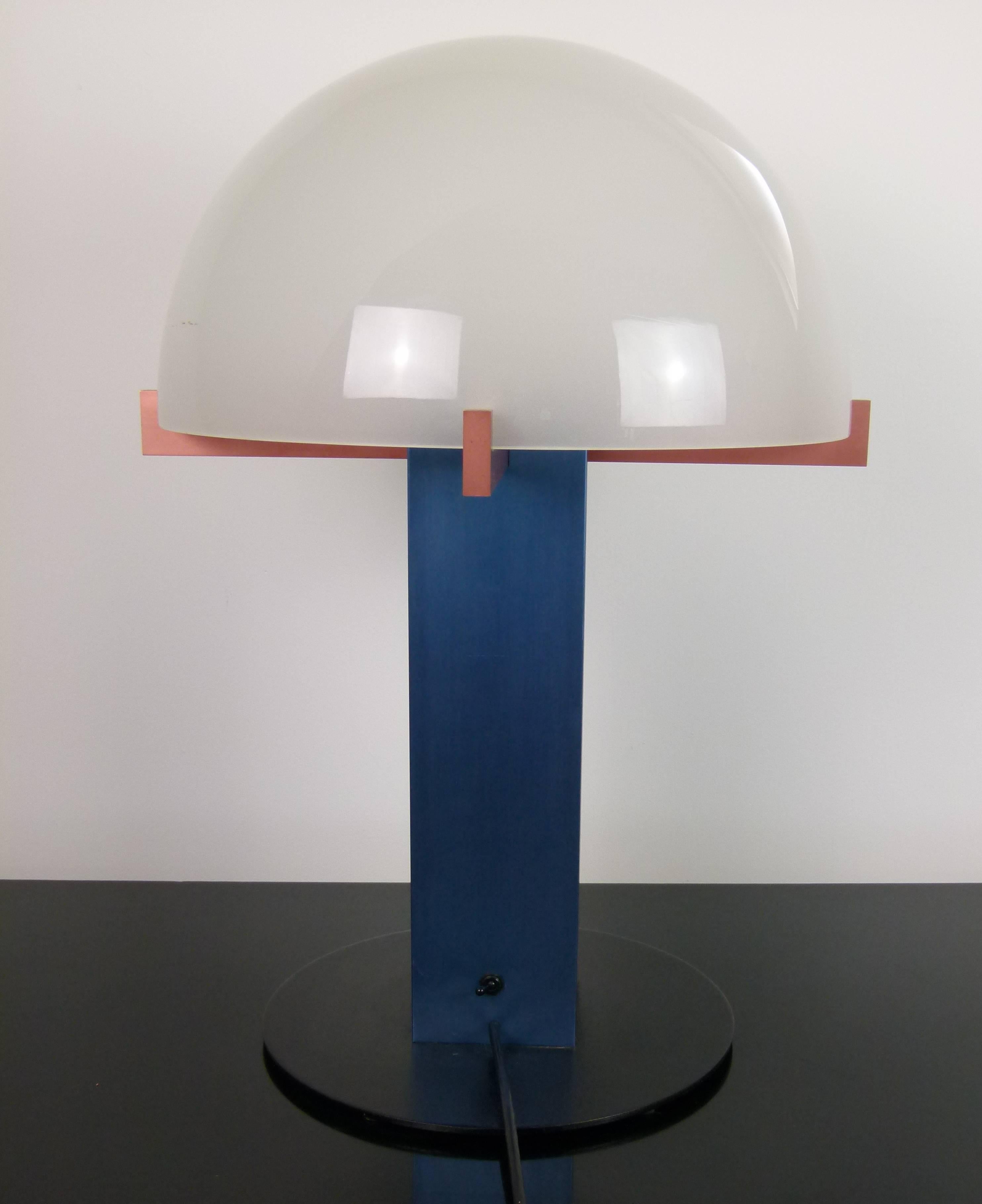 Black lacquered metal and colored brushed aluminium consisting of a black lacquered metal circular foot surmounted by a rectangular trunk in blue color brushed aluminum.
A red color brushed aluminum cross arm is set on the trunk.
A dome-shaped