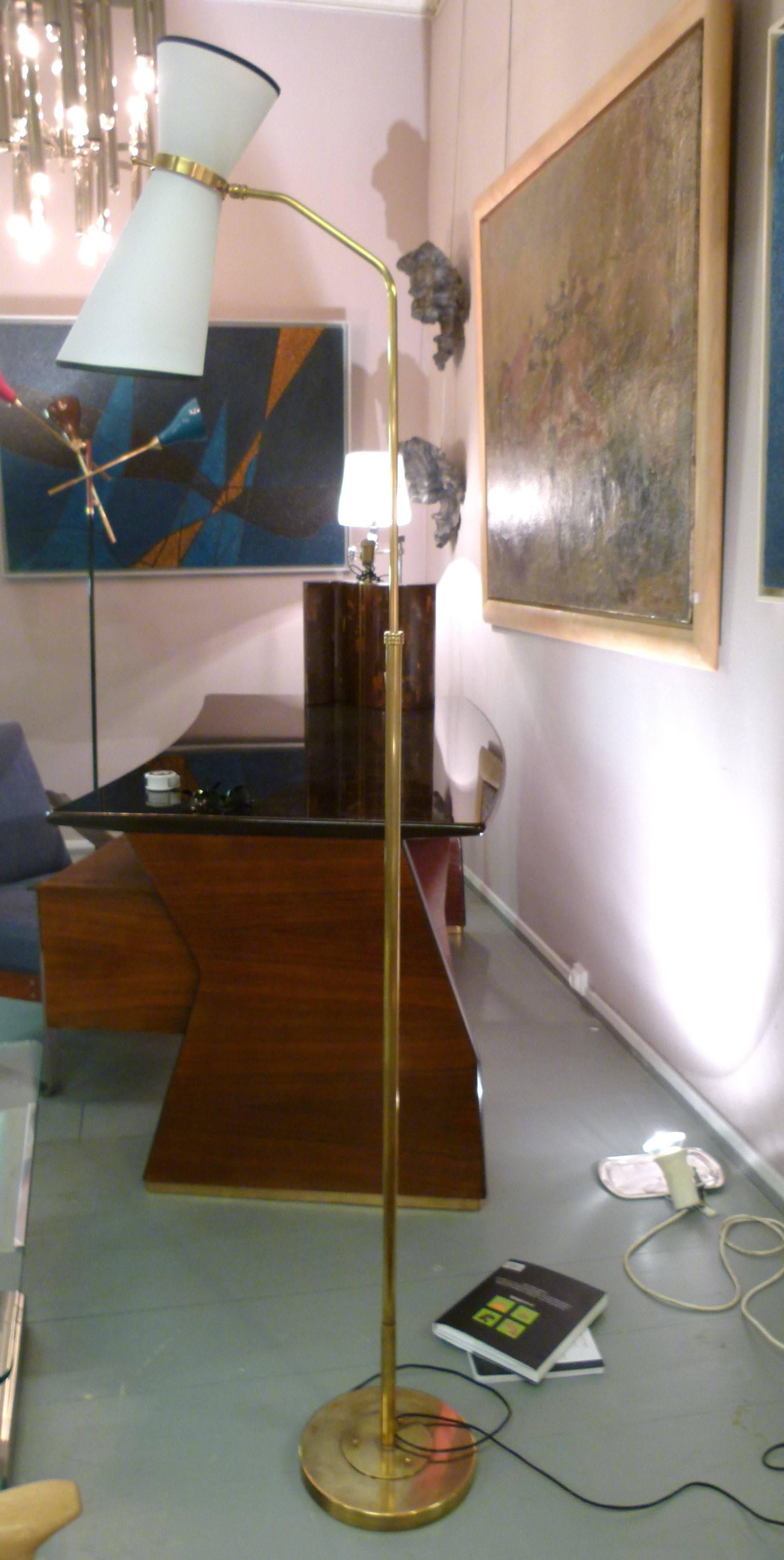 Floor lamp with a double shade mounted on patella.
This floor lamp consists of a brass circular base on which is set a brass lighted arm. Height is adjustable. The upper part slightly curved holds a ring mounted on a solid brass patella.
A brass
