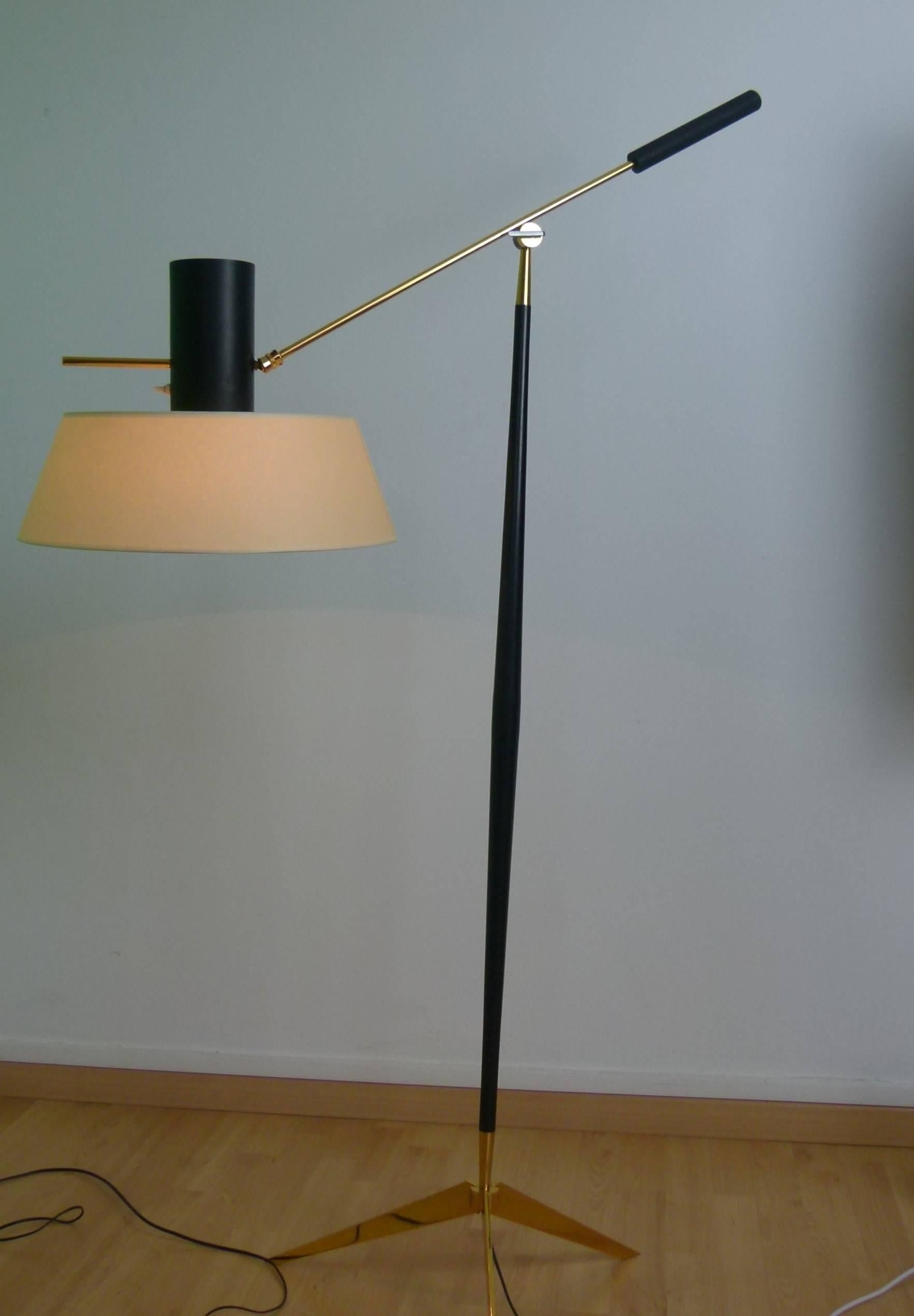 Floor lamp in gilt bronze and black lacquered metal consisting of a gilded bronze tripod on which is set a flared black lacquered metal rod bearing a brass sconce with a counterweight end.
The lighted arm is articulated with brass ball with gun