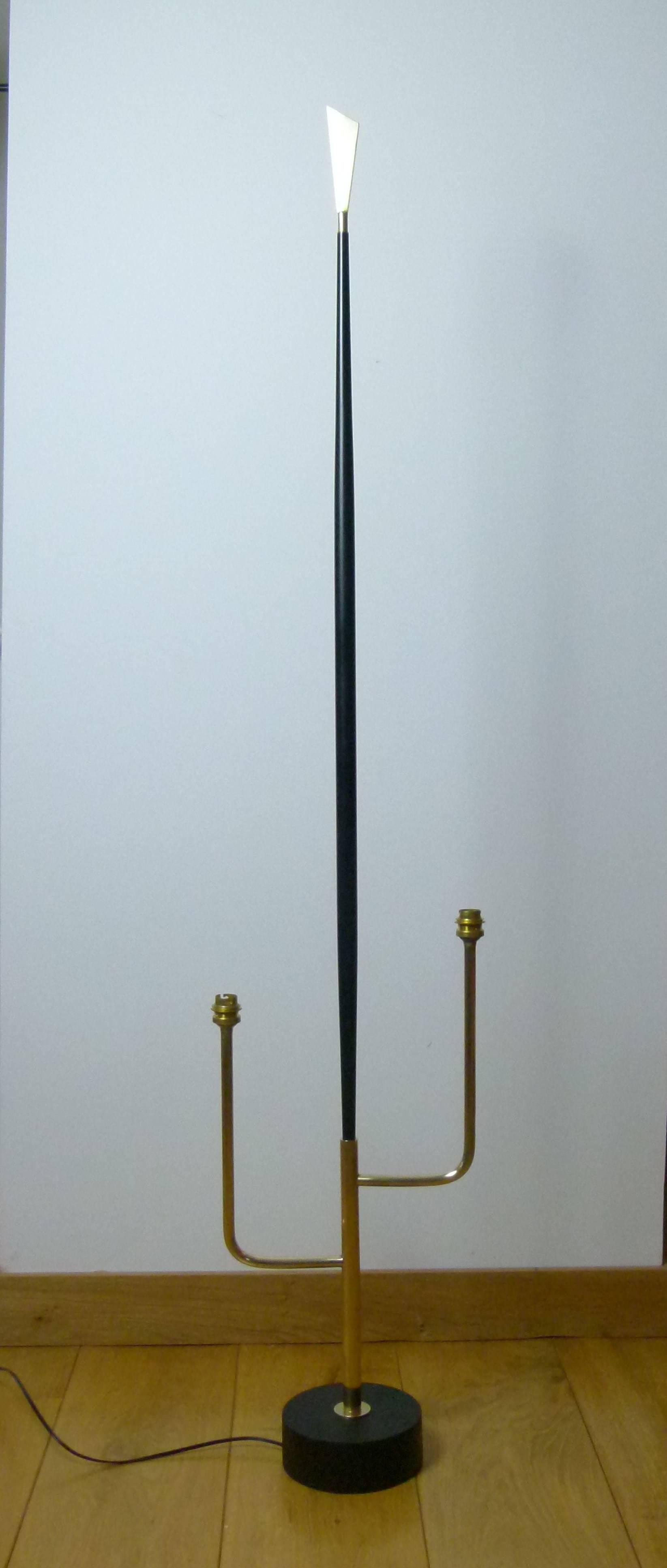 Black lacquer metal and brass floor lamp consisting of a black lacquer metal circular base on which are set two trident shaped lighted arms surmounted by two cylindrical lampshades in offset position.
Another black lacquered arm is set between the