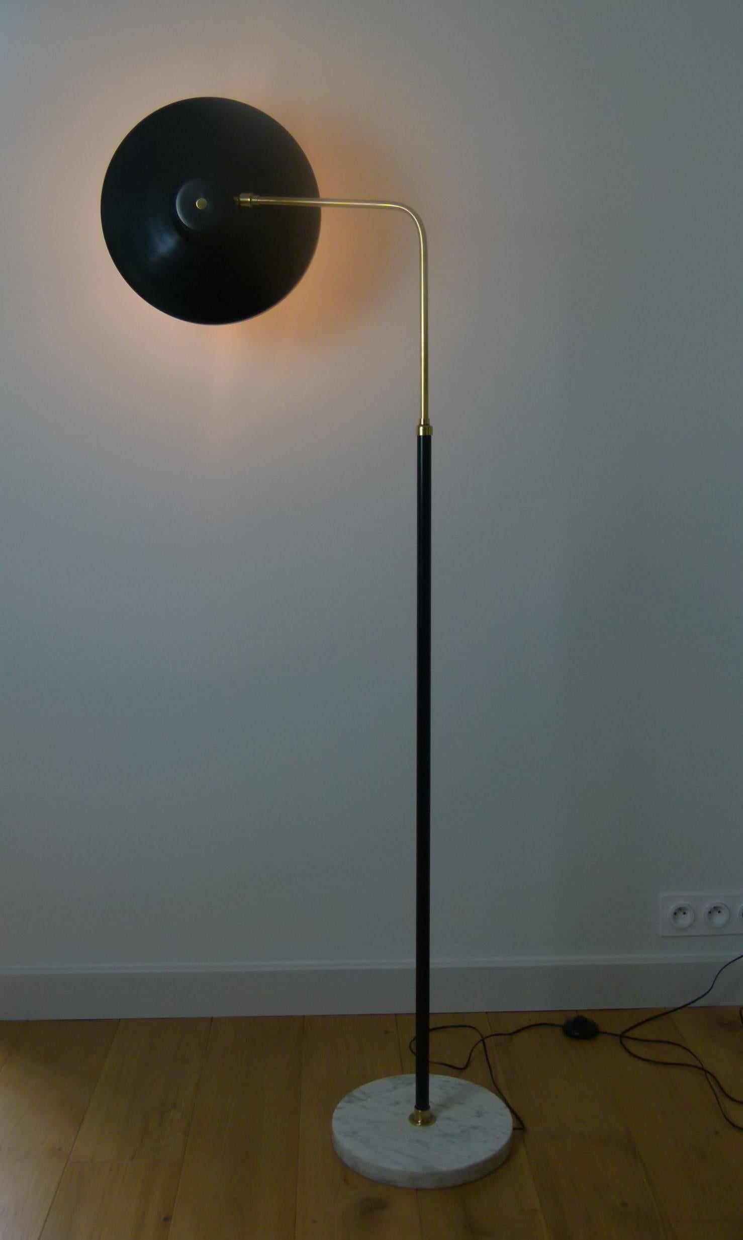 Italian floor lamp in marble, lacquered metal and brass composed of a circular base in marble Italian white veined black on which is set a black lacquered metal trunk mounted on a ring of brass, surmounted by a bended lighted arm with adjustable