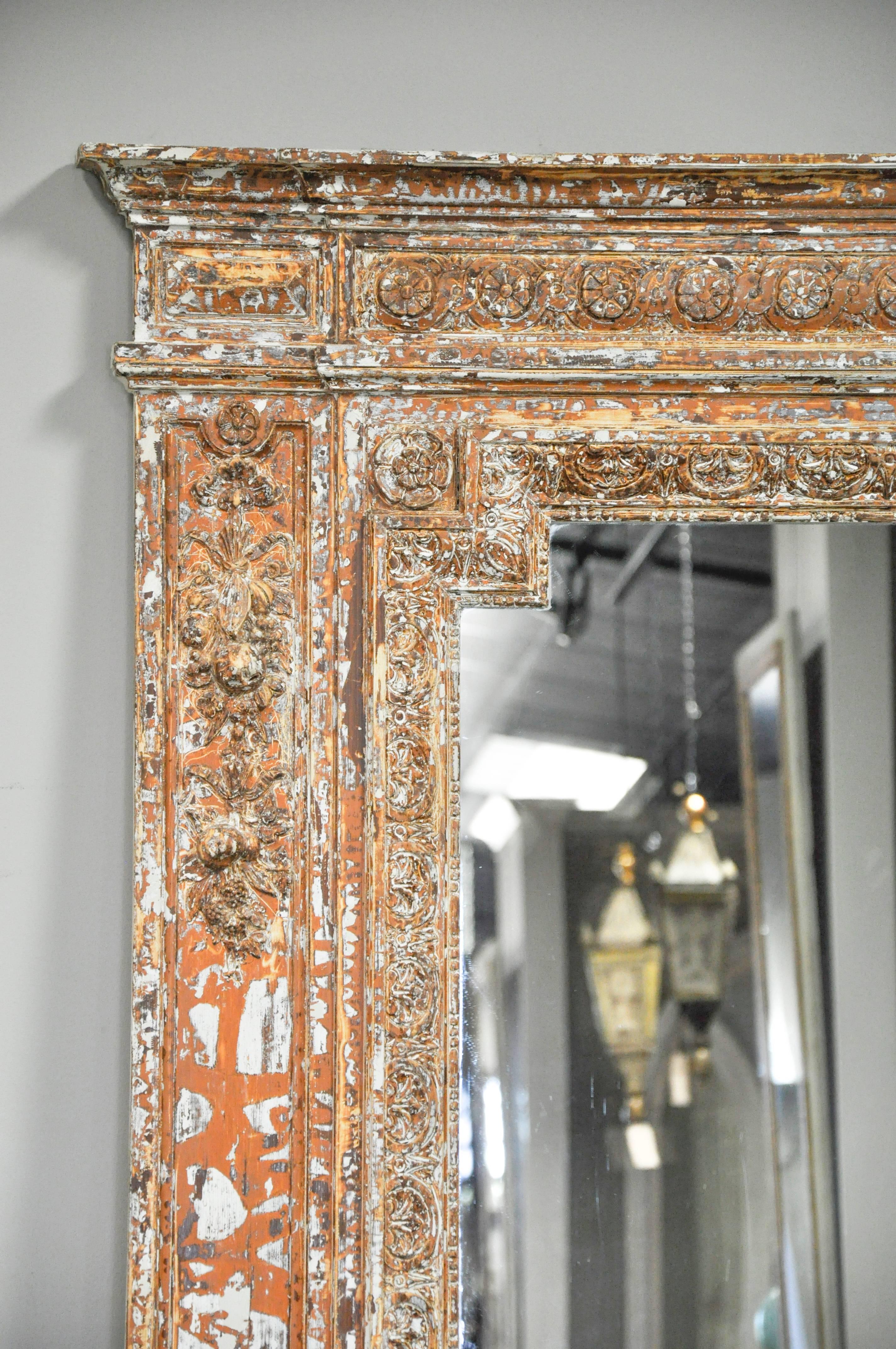 Stunning, oversized 19th century French mirror. The carved frame includes rosettes, floral garland, bow and leaf motif and beautiful molding details. A stripped finish reveals distressed pine and plaster with salmon overtones. Would make a
