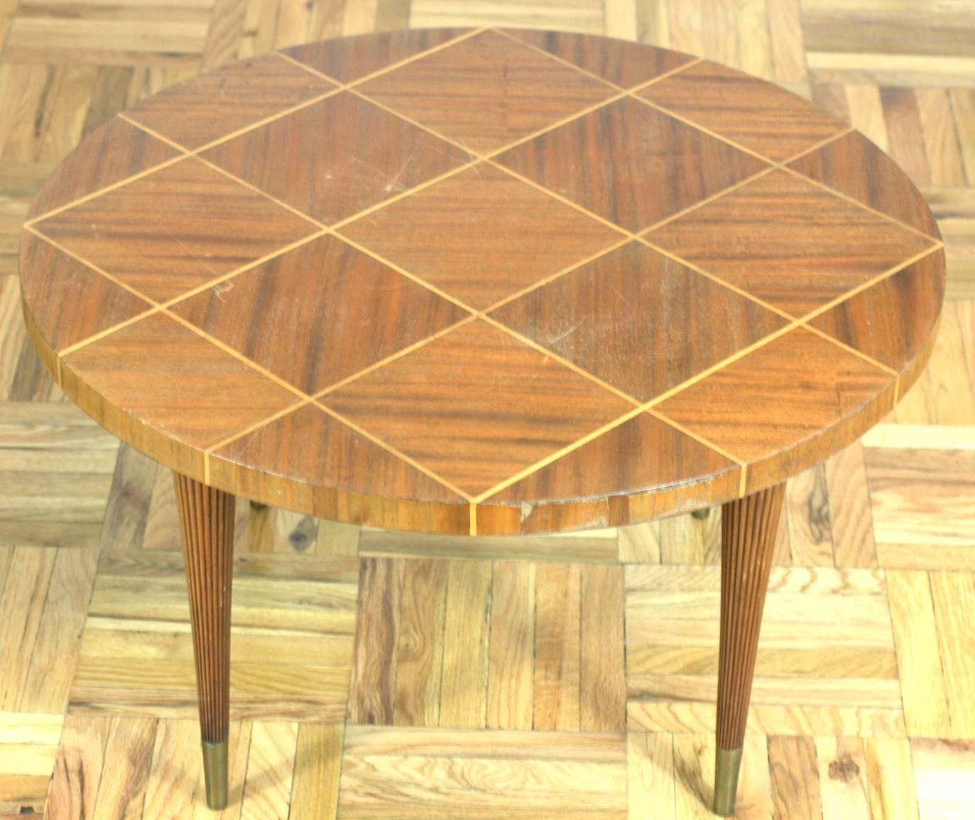 Charak Modern inlaid side / coffee table with tapered reeded legs with gilt metal sabots. Elegant lines featuring a checkerboard patterned parquetry round top of inlaid contrasting toned woods. 
Most images show table in original condition, however,