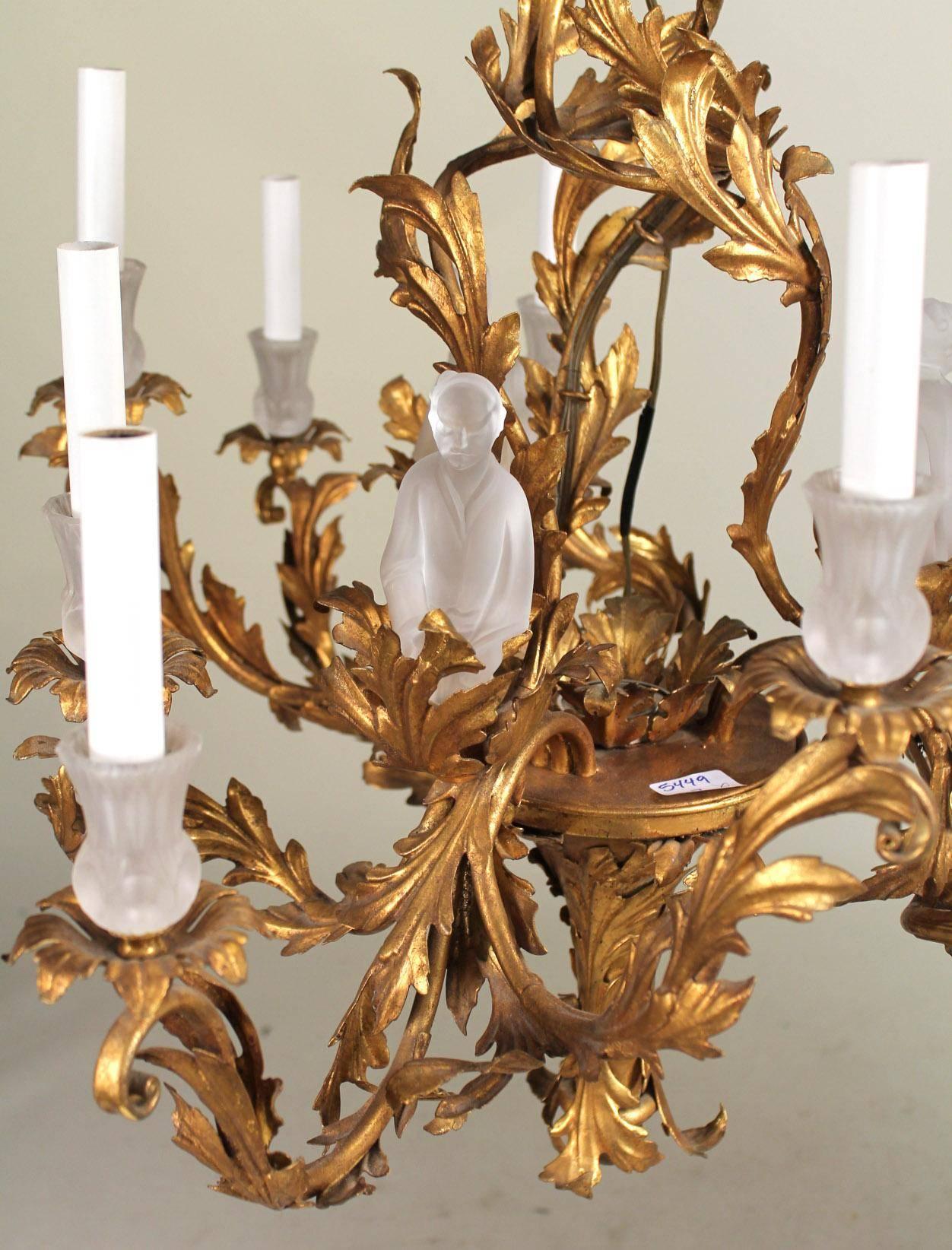 Unusual gilt chinoiserie chandelier in the Baroque taste from the 1980s, Italy.
Frosted glass figures of Asian wise men are set into the gilt Roccoco style leaf work settings. Additionally, frosted glass 