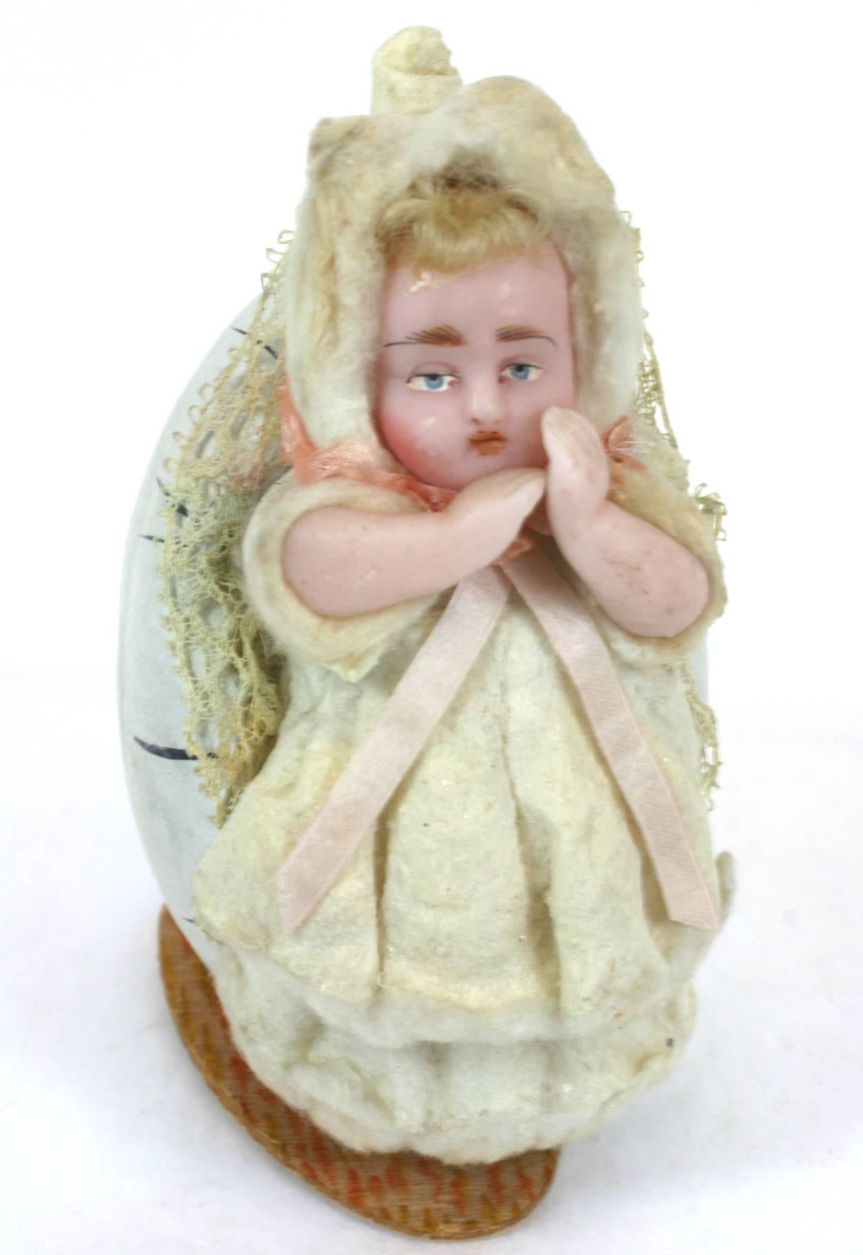 German wax baby candy container from the late 19th century. A realistically formed egg of paper and plaster with a fully detailed and dressed wax baby nestled inside. Charming subject matter and lovely detailing, down to the hand knitted stocking.