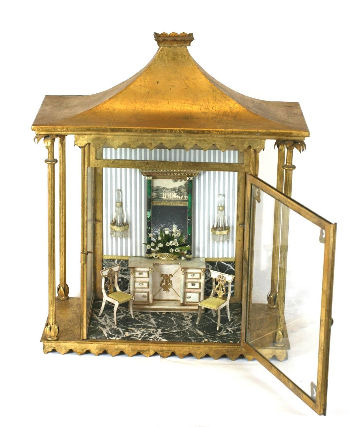 Gilt tole wall diorama with finely detailed period interior. Chairs, mantel, floor and decorations are all finely crafted from hand-painted paper and are moveable. 
Gilded pagoda form roof with side columns capped with leafy gilt caps. Lovely