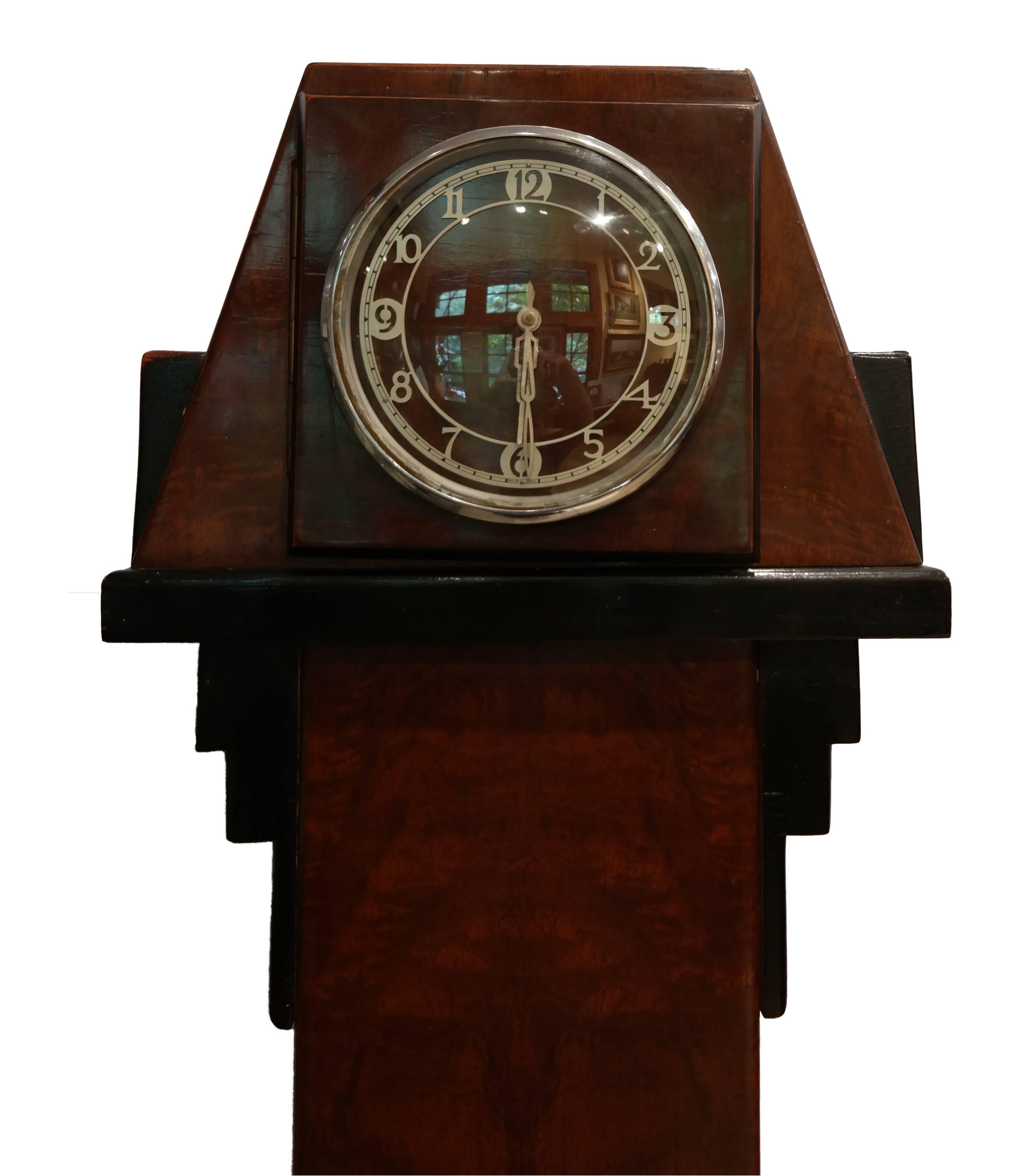 1930s deco grandmother clock radio. Constructed from figured walnut with faux ebony decoration and a brushed steel dial. Speaker in centre of clock body.

Handcrafted by British Tempovox 

Base measurement: 8.5" x 13" (D x W).
   