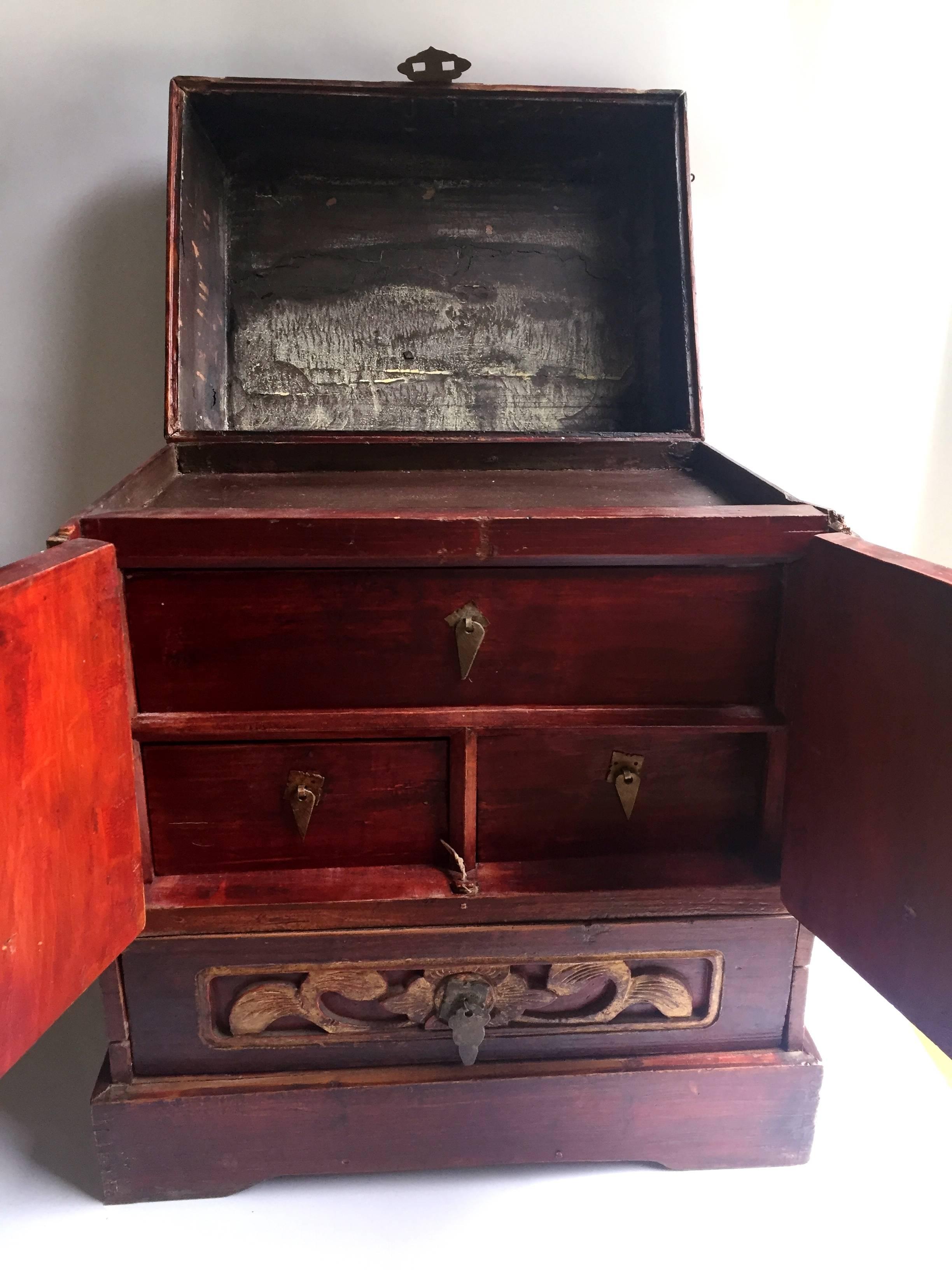 Beautiful red lacquer jewelry box features 4 drawers and a space under the lid for storage. The most interesting thing about it is the tiny locking peg that discreetly locks the bottom drawer. Carved Harmony Gods on the doors symbolize peace and