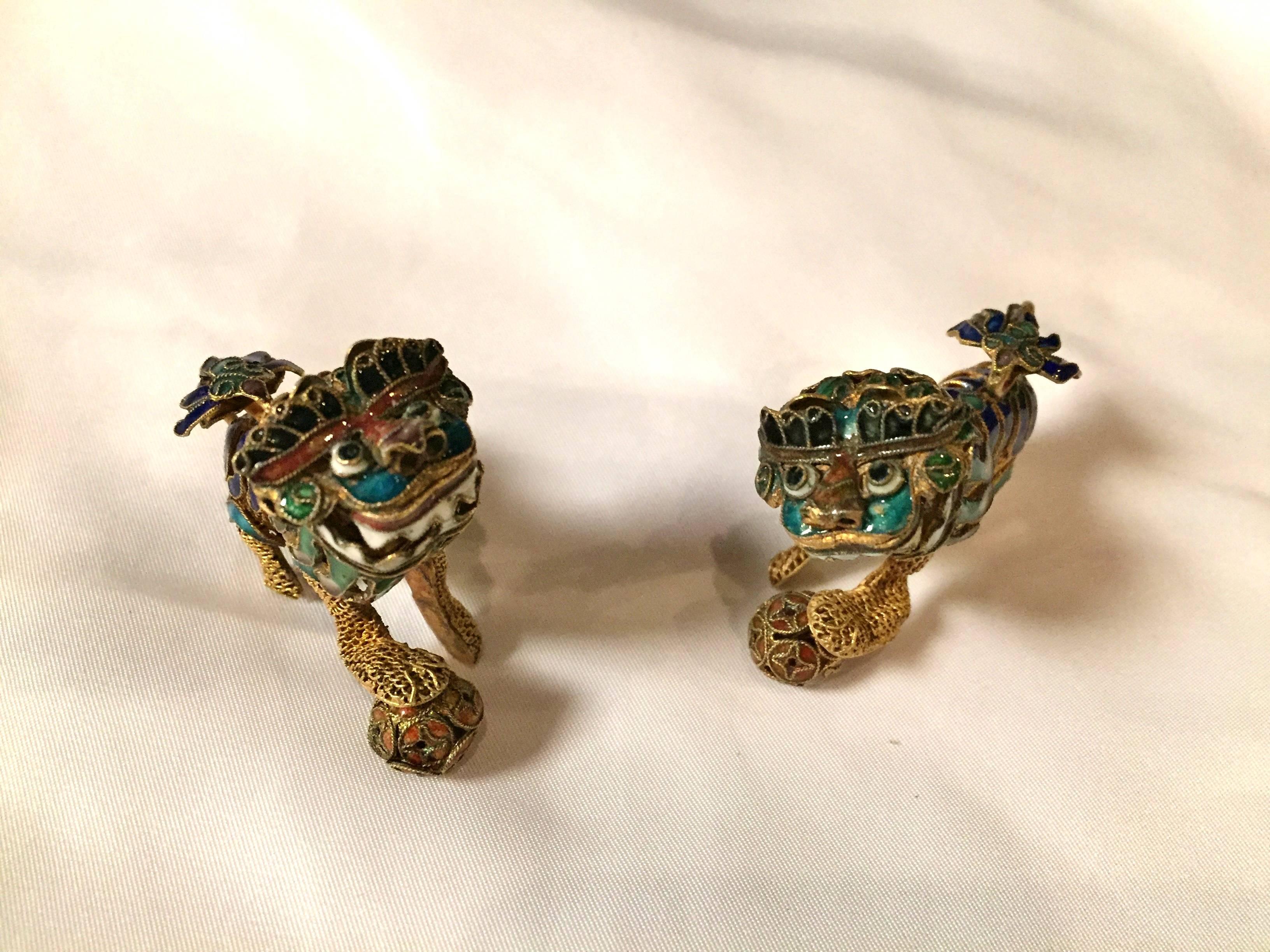 This pair of enamel foo dogs are exquisite. Their heads and one of the balls move with motion. The balls feature enameled coin patterns and are finely trimmed with brass wires. The colors used here are turquoise, lapis, dusty rose and white. The