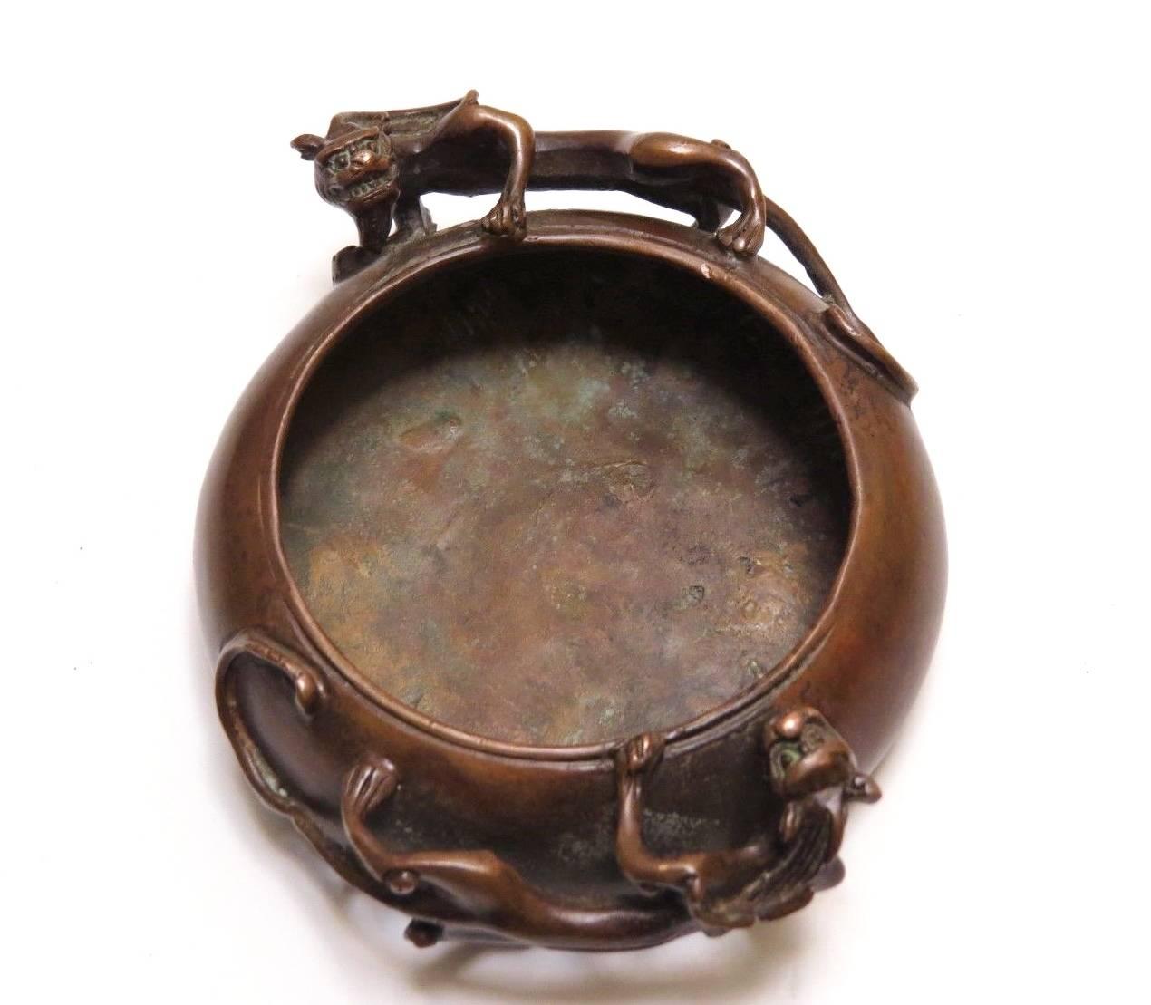 Stunning bronze bowl is both an incense burner and a washer used to hold water for calligraphy painting. 

The pair of dragon like animals, called 