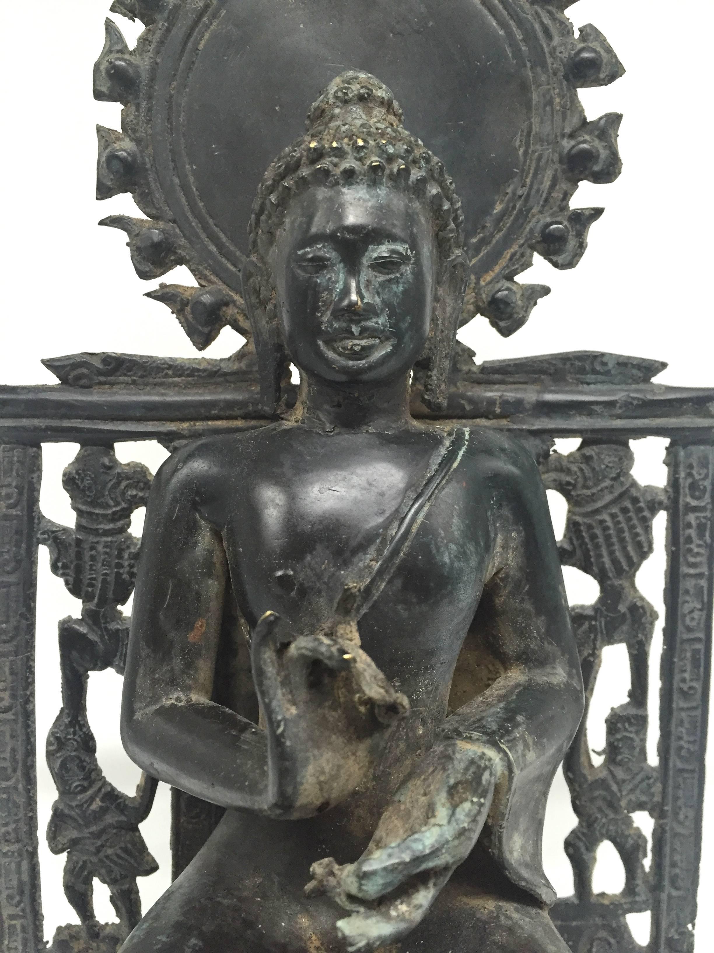 An exquisite late 20th century Burmese bronze Buddha.

The Buddha is seated on a throne with two lions anchoring the base. His back features beasts and warriors with a halo above and behind. His ankles are together with a decorated sash draping down