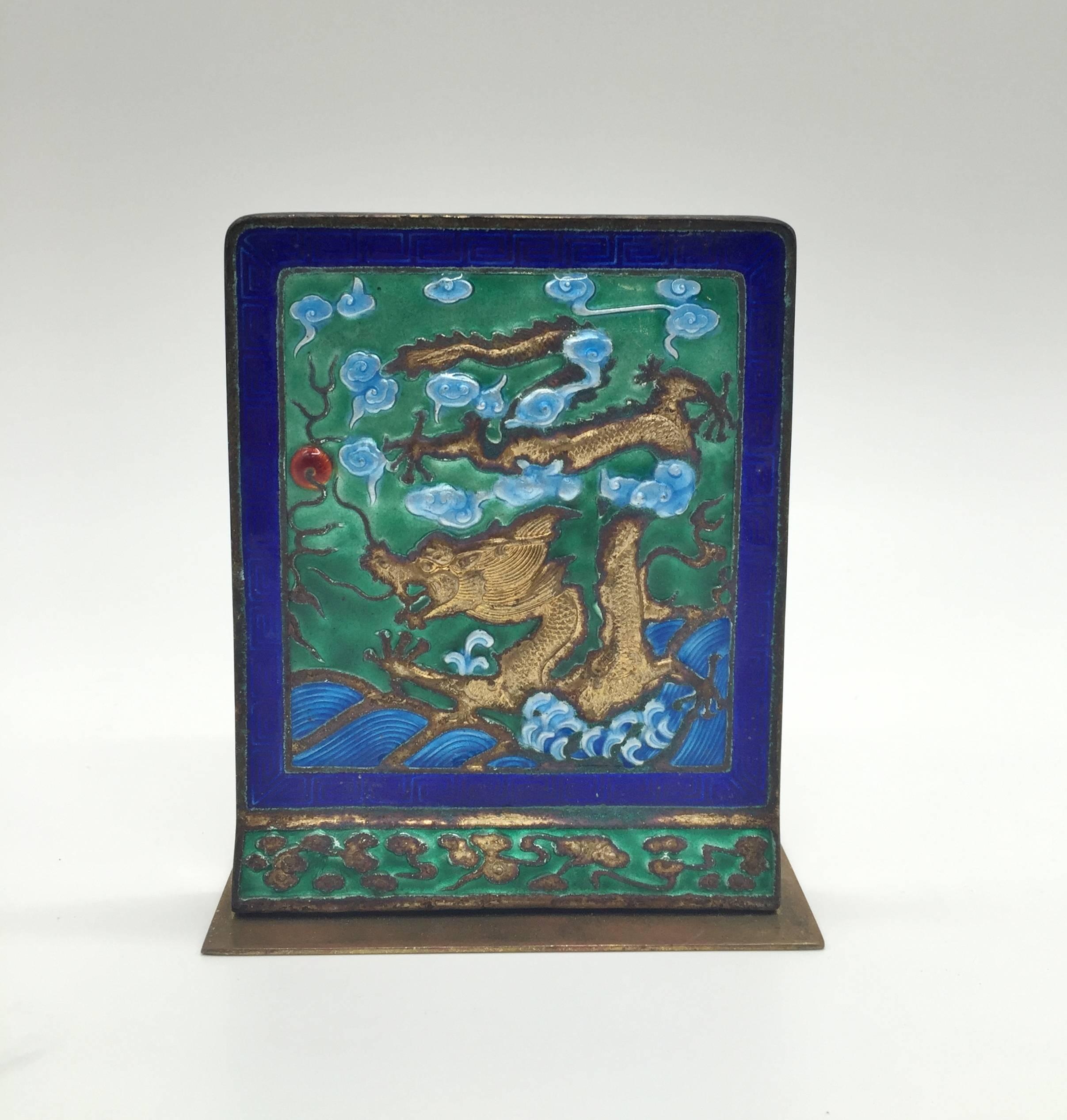 This is an exceptional example of Chinese enamel. 

The artwork is of a water dragon pursuing a fire ball in clouds. He rises from the ocean and goes after the ball aggressively with his paws ready for action. The dragon is gilded and very