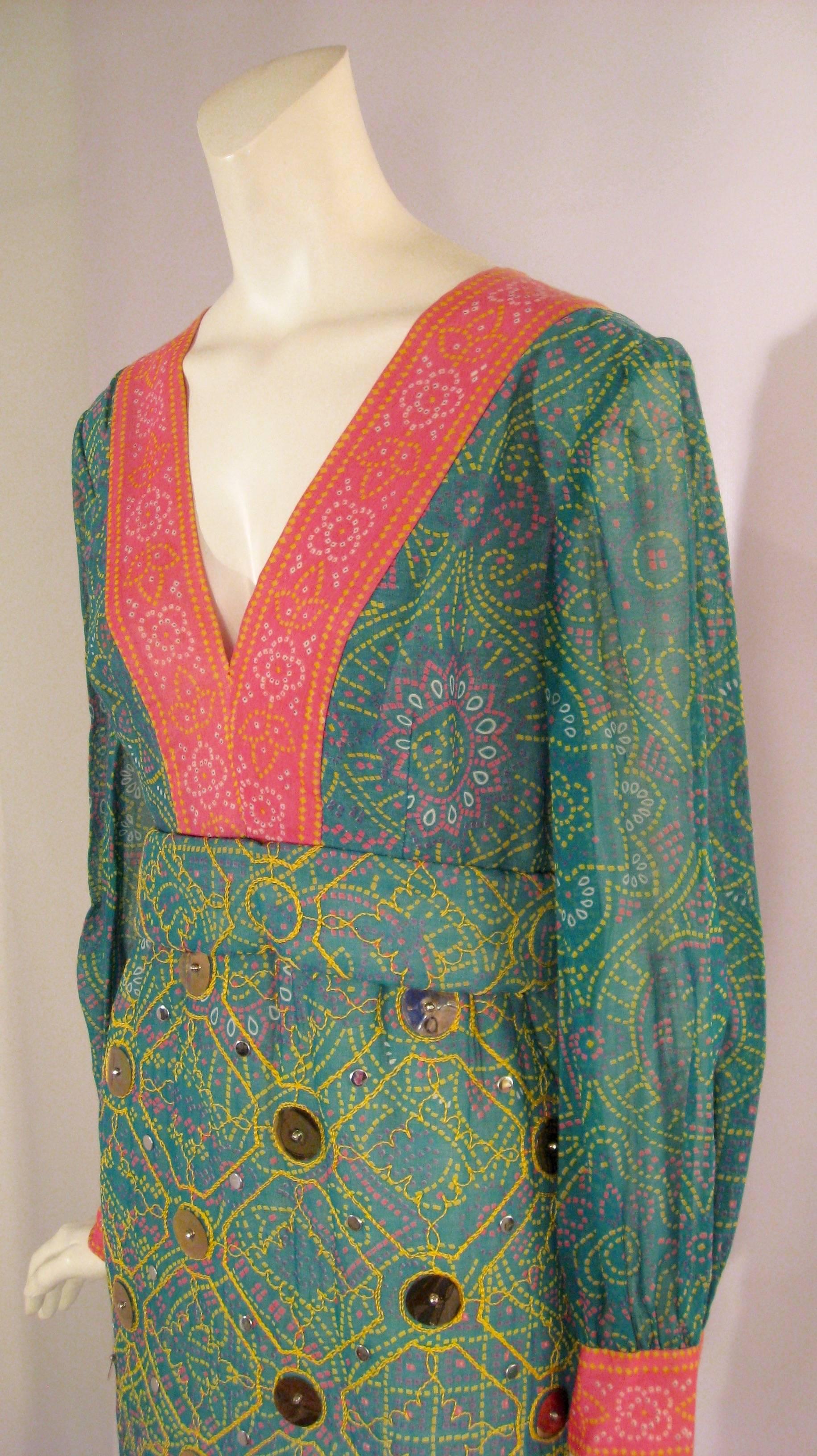 Gorgeous 1970s dress in an ethnic print. The main color is a tealy green with pink, yellow, white and purple printing. The cuffs, neck and border bottom are a hot pink with yellow, white and green printing. The A line skirt is quilted and interlined