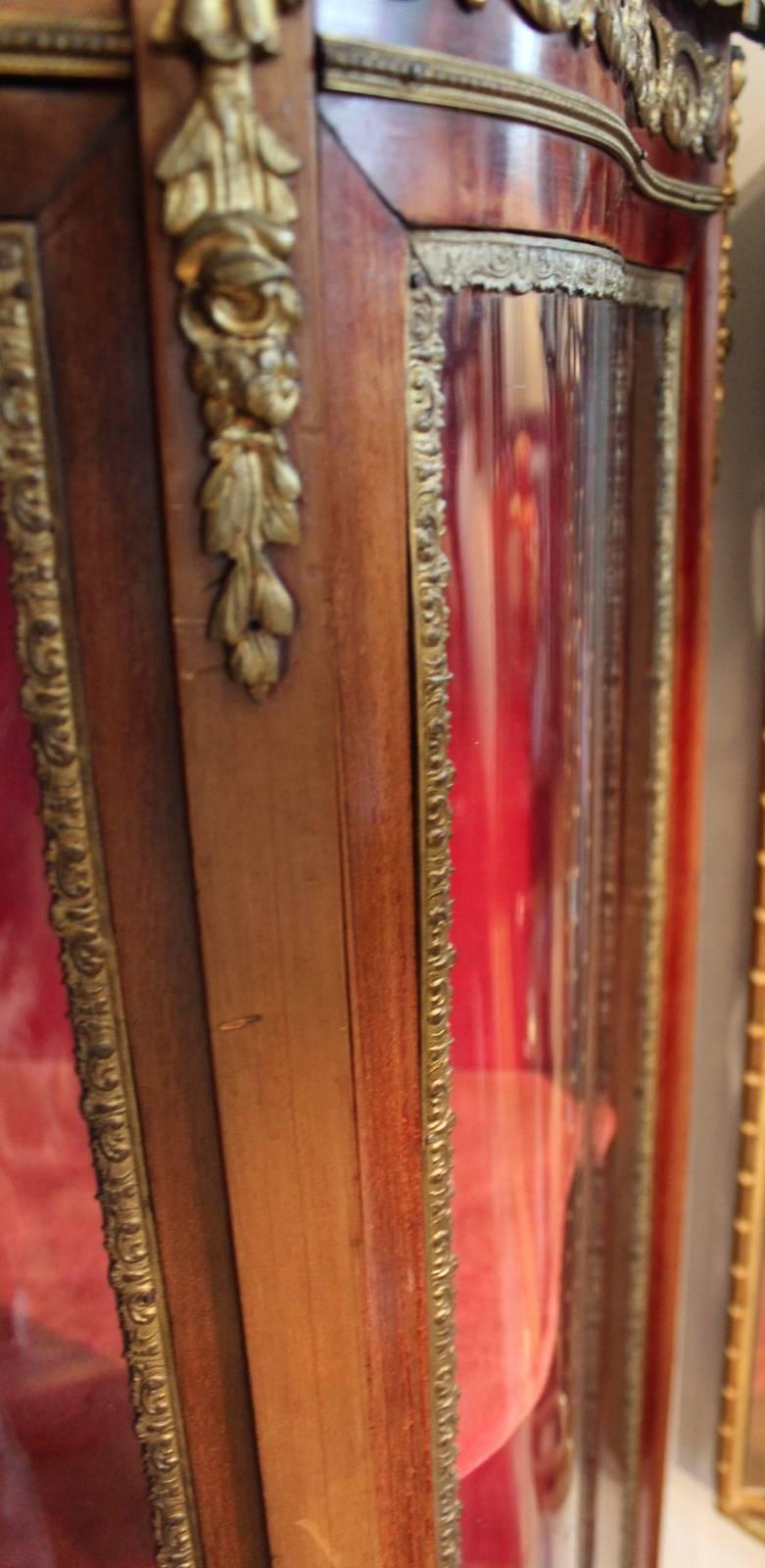 Classically styled French vitrine curio cabinet with gilt bronze mounts. The rouge marble top is surrounded by a pierced gallery trim. A single hinged door flanked by two curved side glass stationery panels all testing on four cabriole legs. The