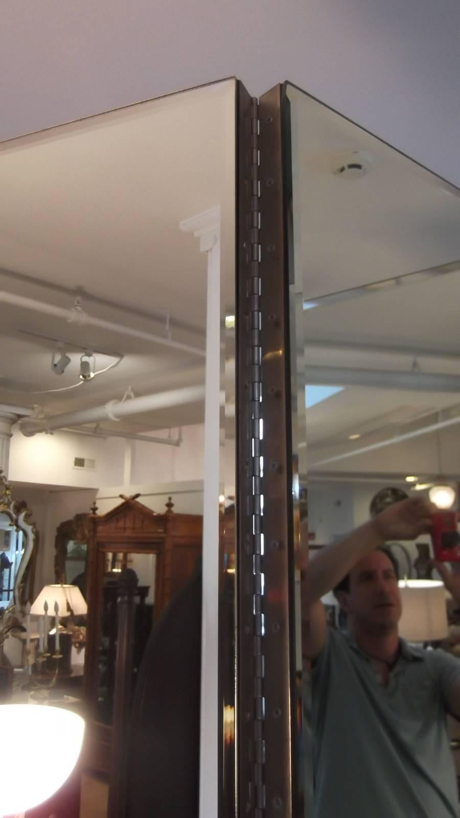 A glamorous four-panel beveled mirror room divider or screen. A generous size with sturdy piano hinges, this screen stands 84