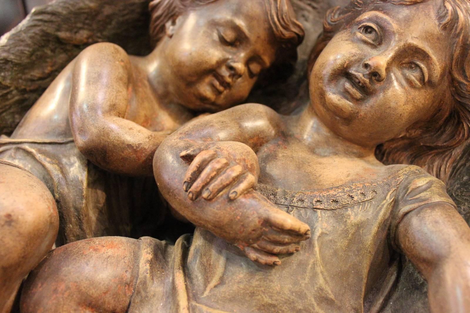 Large unique Austrian terracotta sculpture of playful infants in draped basket of twigs. Two infants side by side centered on a realistically detailed basket with twig feet.