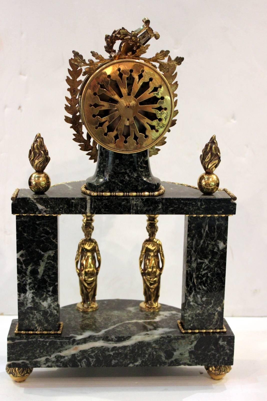 Recently serviced demilune shaped verdigris marble mantel clock. The clock with musical themed finial rests on a columned body consisting of two female figures in a neoclassic style, the back columns are marble with lyre mounts. The entire clock
