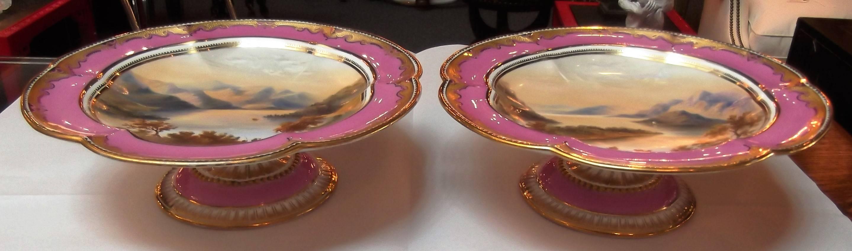 A pair of antique English hand-painted and raised gilt compotes. Each one is painted a different United Kingdom seaside landscape. One is Connemara where you “experience the real beauty of Ireland”. It's located in the North West corner of County