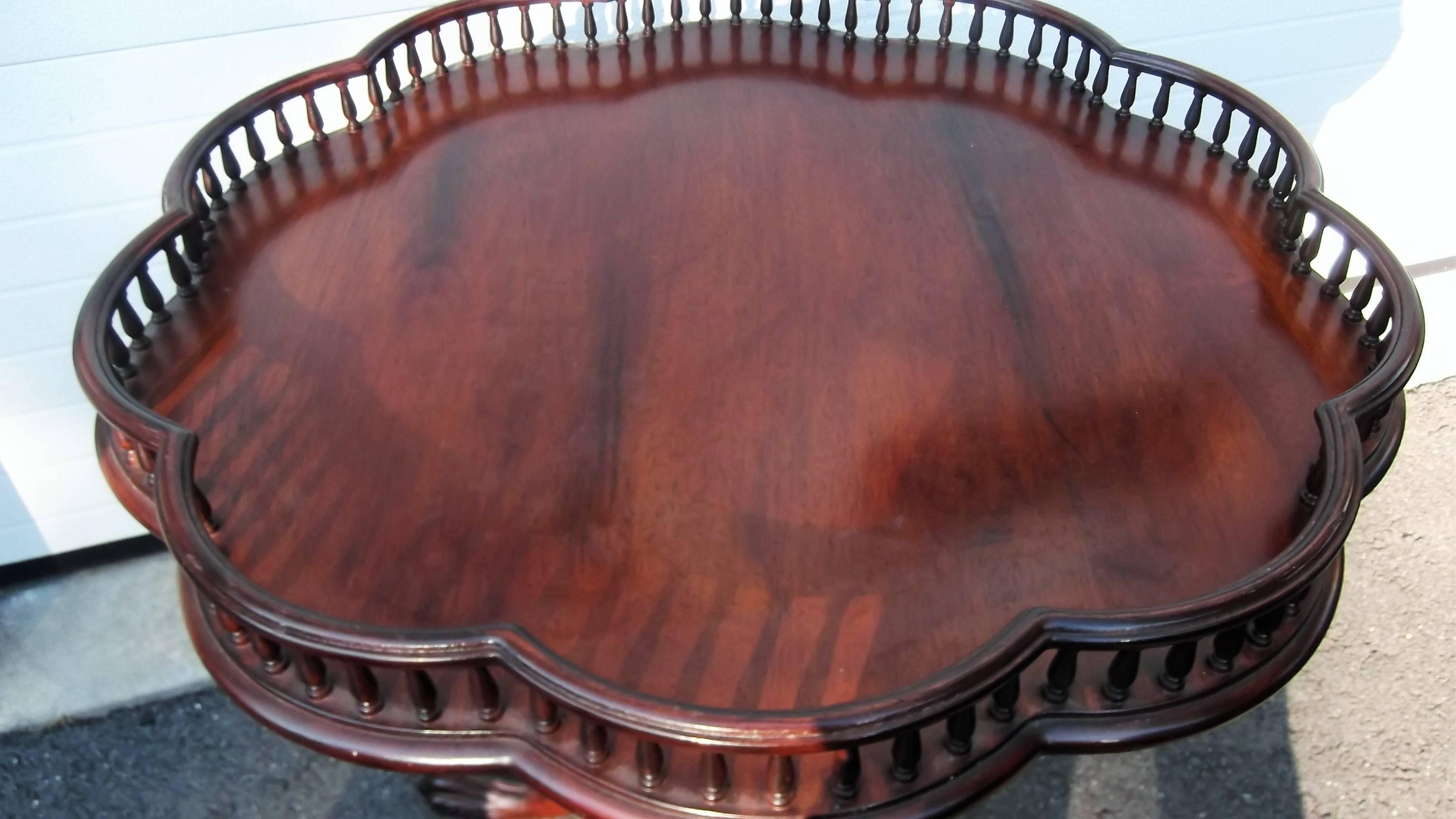 Mahogany table with scalloped gallery edge top. A center carved column resting on three carved paw foot legs. Solid mahogany with a nice reddish brown finish.