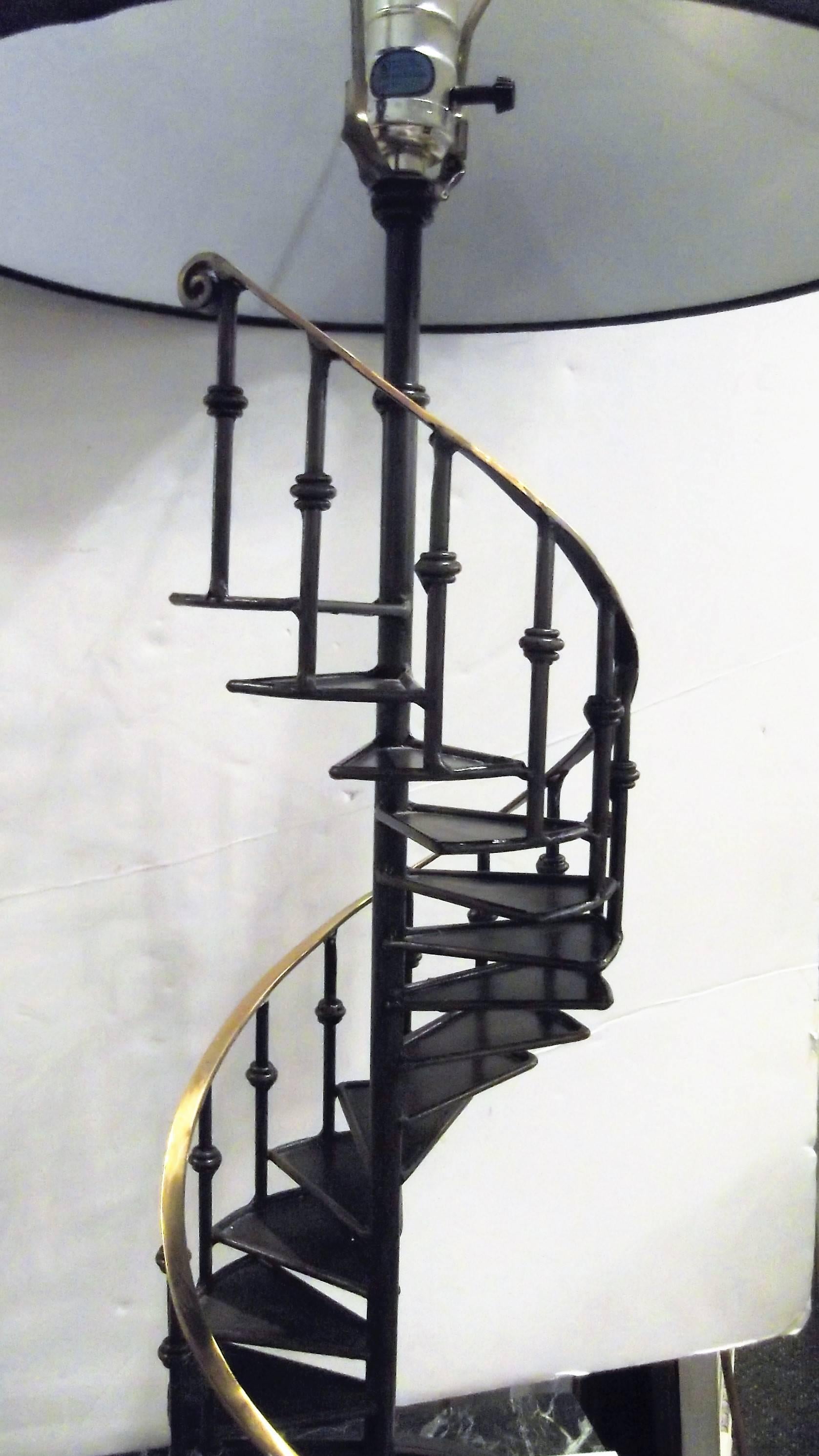Patinated and polished brass architectural model of a spiral staircase as a lamp. This is a decorator item made for Palecek of NYC. Very high style with a curved polished hand rail accent. Topped with a simple black fabric drum shade. The lamp to