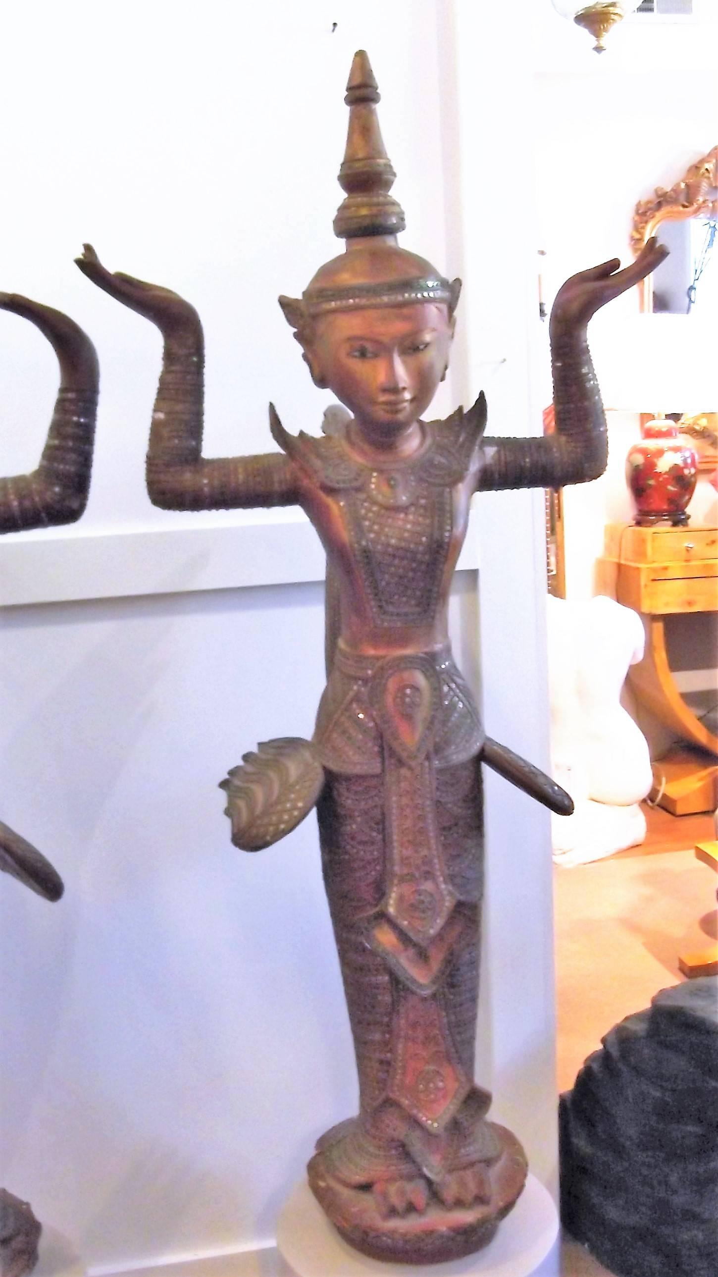 A pair of carved wood and gilt Goddess sculptures made in Thailand. Each one is attached to a custom round wood pedestal base. The figures are decorated with small round mirrored jewel and raised textured details. The antique female subjects are in