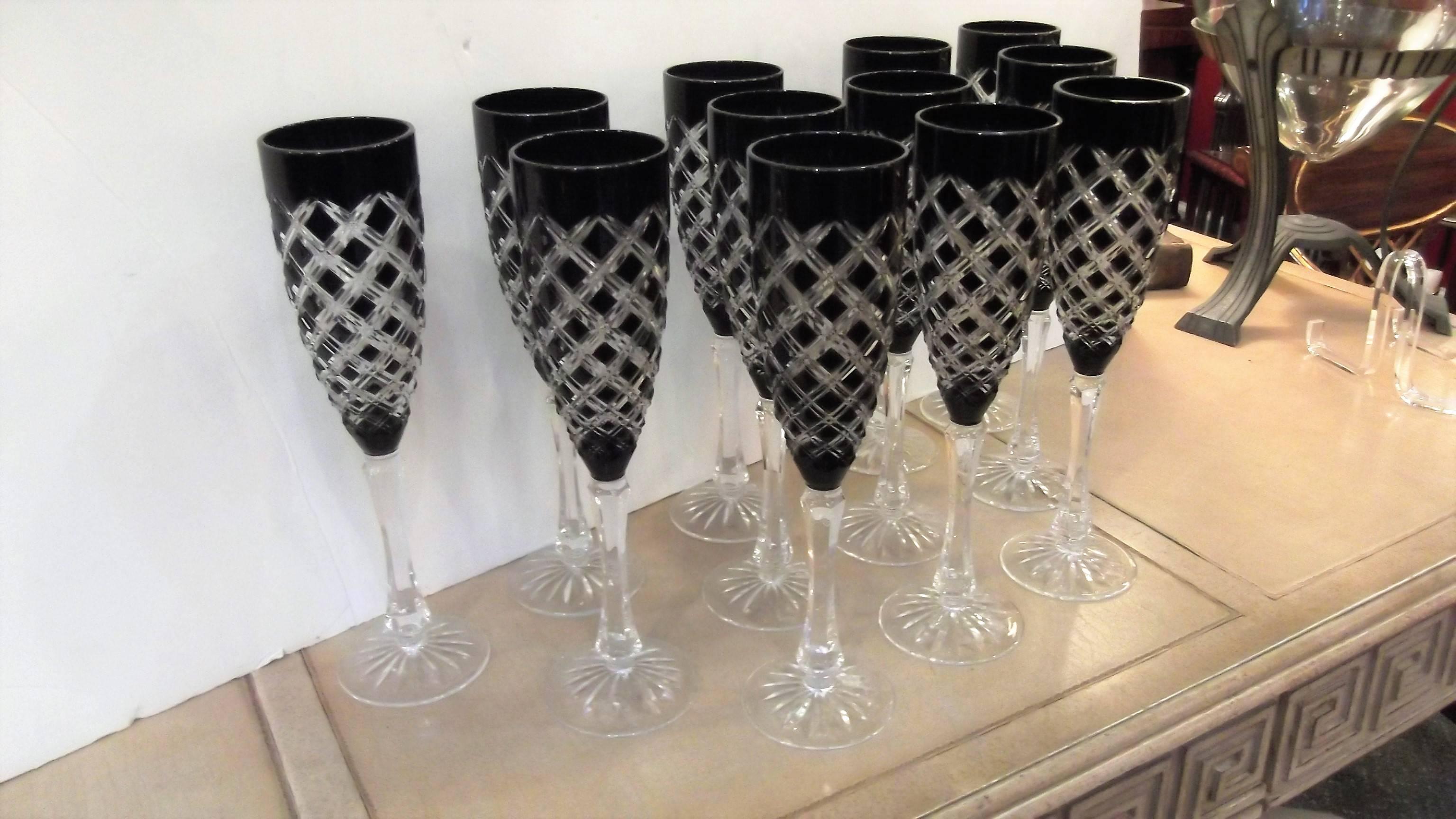 Elegant set of 12 cut-glass champagne flutes with a black amethyst glass overlay. The black amethyst is dark and only reveals the deep purple under bright light. The dark glass is then cut back to reveal the clear glass. A nice and tall 10.5