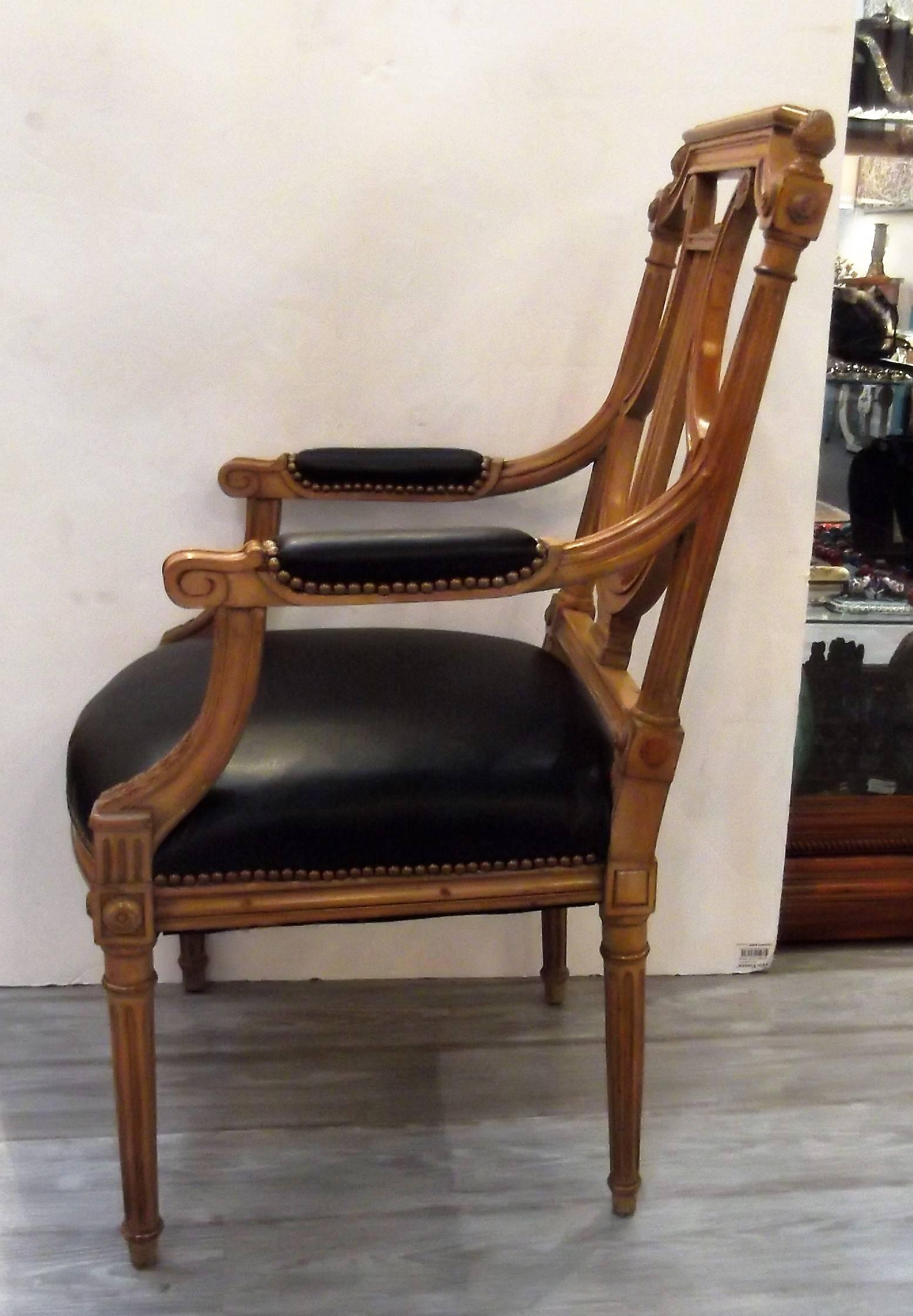 Classic Louis XVI style armchair with lyre back. The sturdy hand-carved frame of yew wood is newly covered in black leather with antiqued nailhead trim.