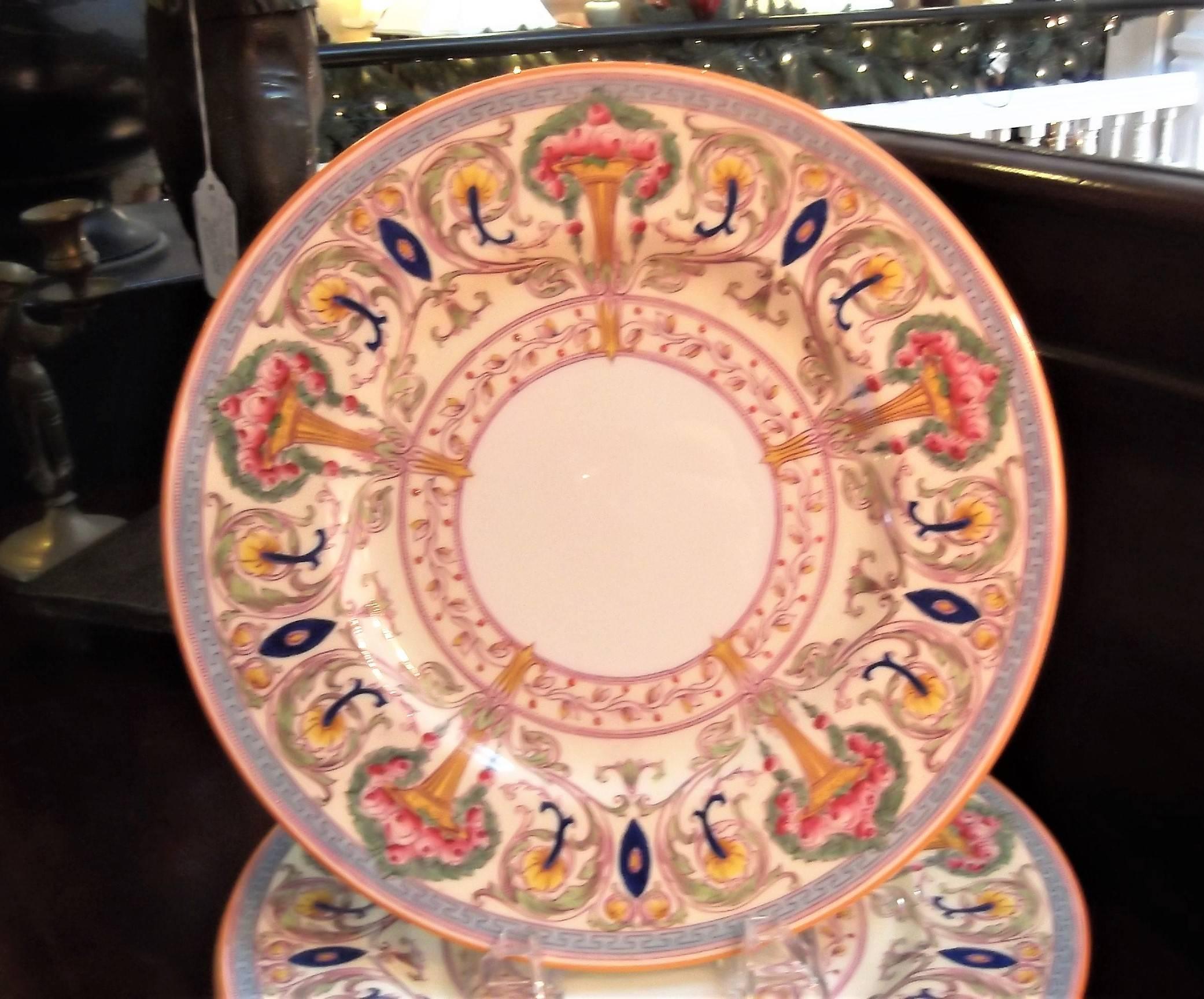A set of 12 hand enameled and painted vibrant service plates made by Royal Worcester England. The fanciful borders include urns and bouquets and intricate details. The wide border is a light vanilla background with a white center. The year mark is a