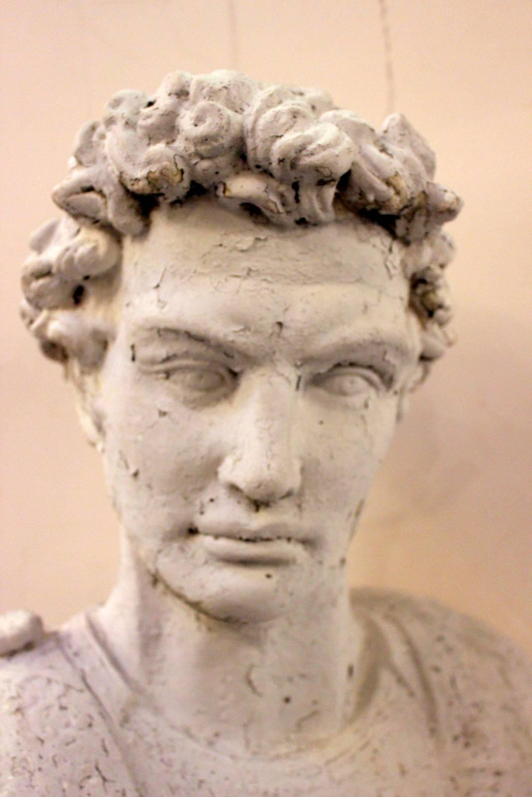 Neoclassical bust of Alexander the Great with aged and chipped painted finish. The solid cement bust rests on a round carrara marble base which was of a later date. The bust is early 20th century around 1920s.