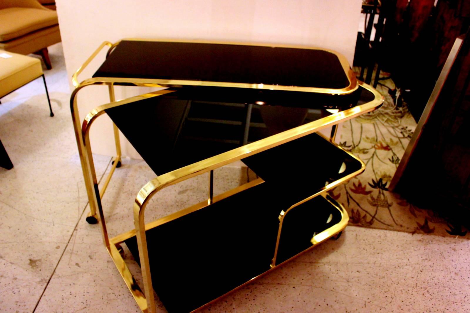 An exceptional, expandable, brass and black glass bar or tea cart by Milo Baughman for Design Institute of America, circa 1970. Double the space for serving.
Opens to 7 feet. With brass casters.