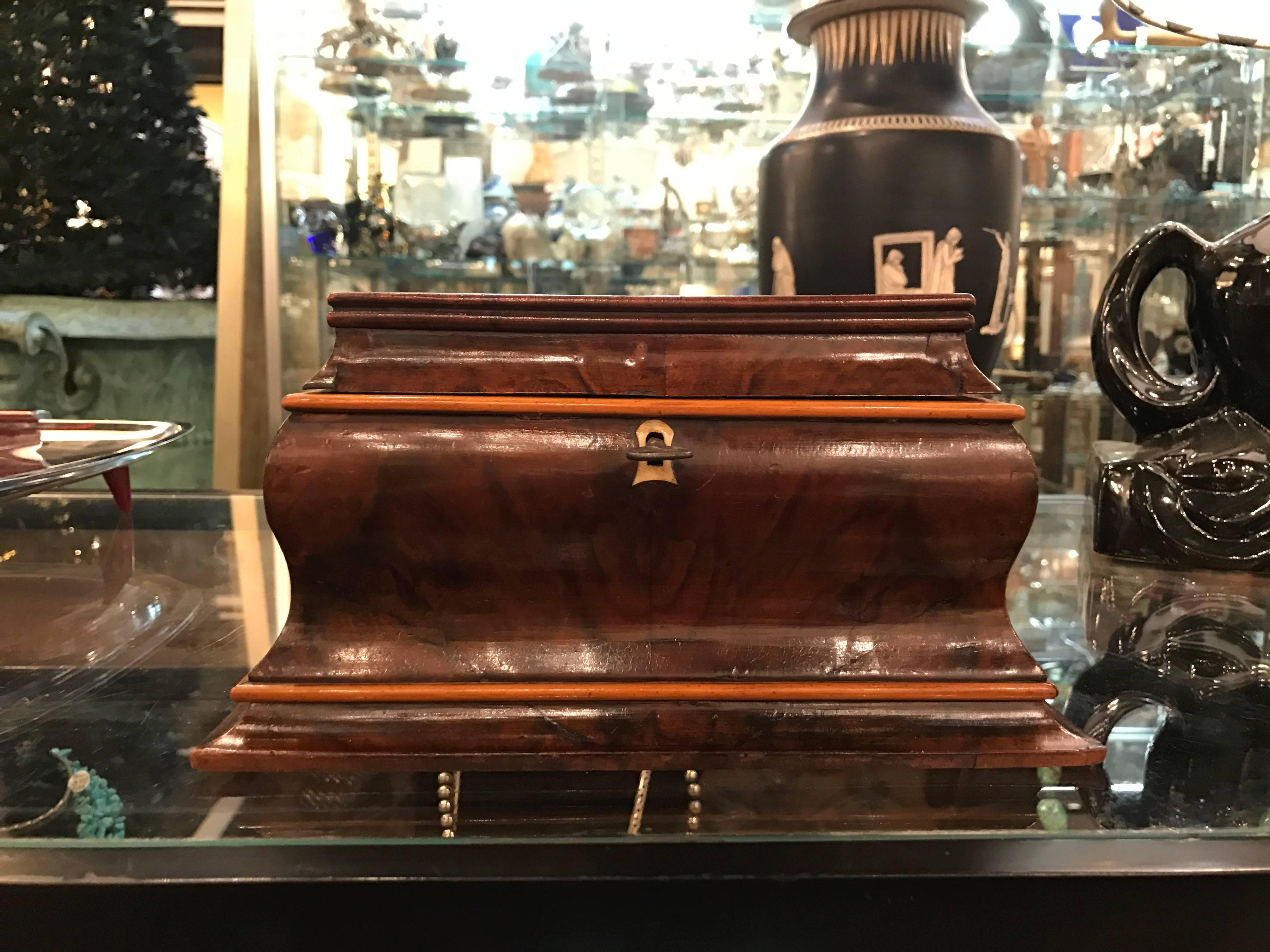 Shapely hinged lid box with figurative walnut wood exterior. The fitted tray is maple with an interior mirror and lower storage. The key is original and the lock is working.