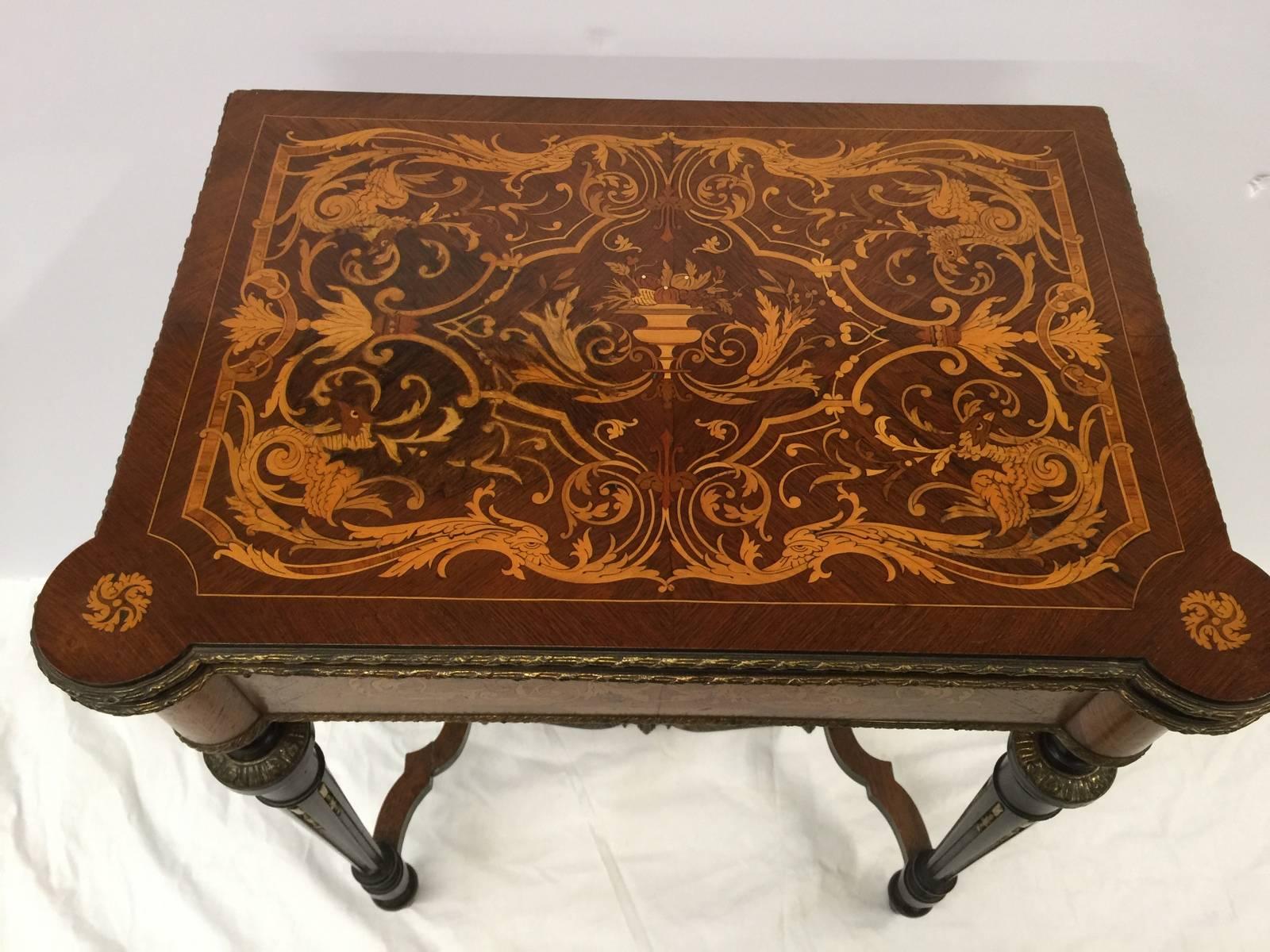 Gorgeous mahogany inlaid flip-top console card table with elaborate satinwood inlay. Hand-carved tapered legs with stretcher base with ormolu mounts. The black leather top is in very clean condition with minimal signs or use.