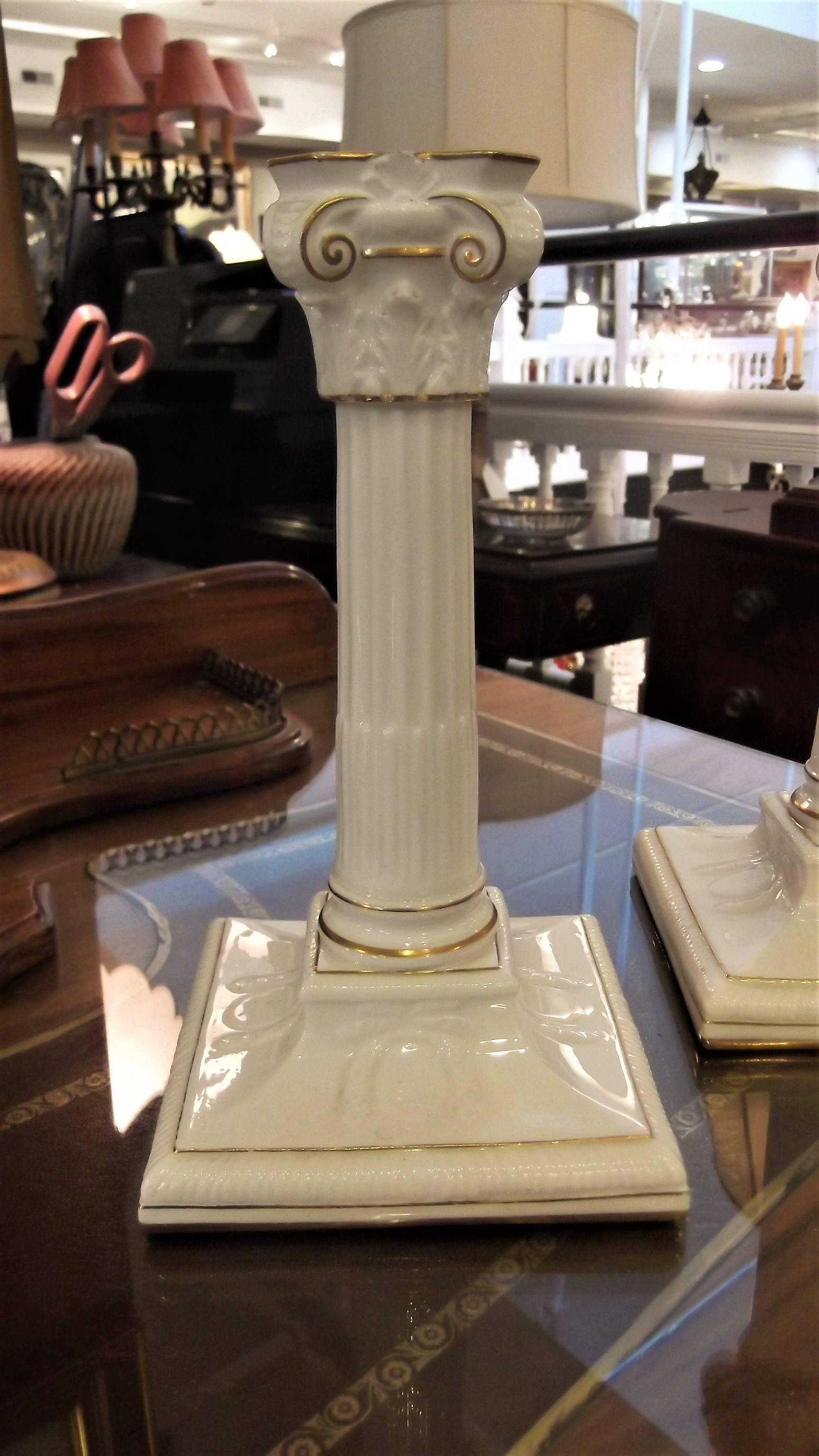 A pair of neoclassical cream white with gilt decoration candlesticks. Made by Royal Worcester circa 1900, in the form or Corinthian columns Creamy almost white backgrounds with delicate touches of hand applied gold.