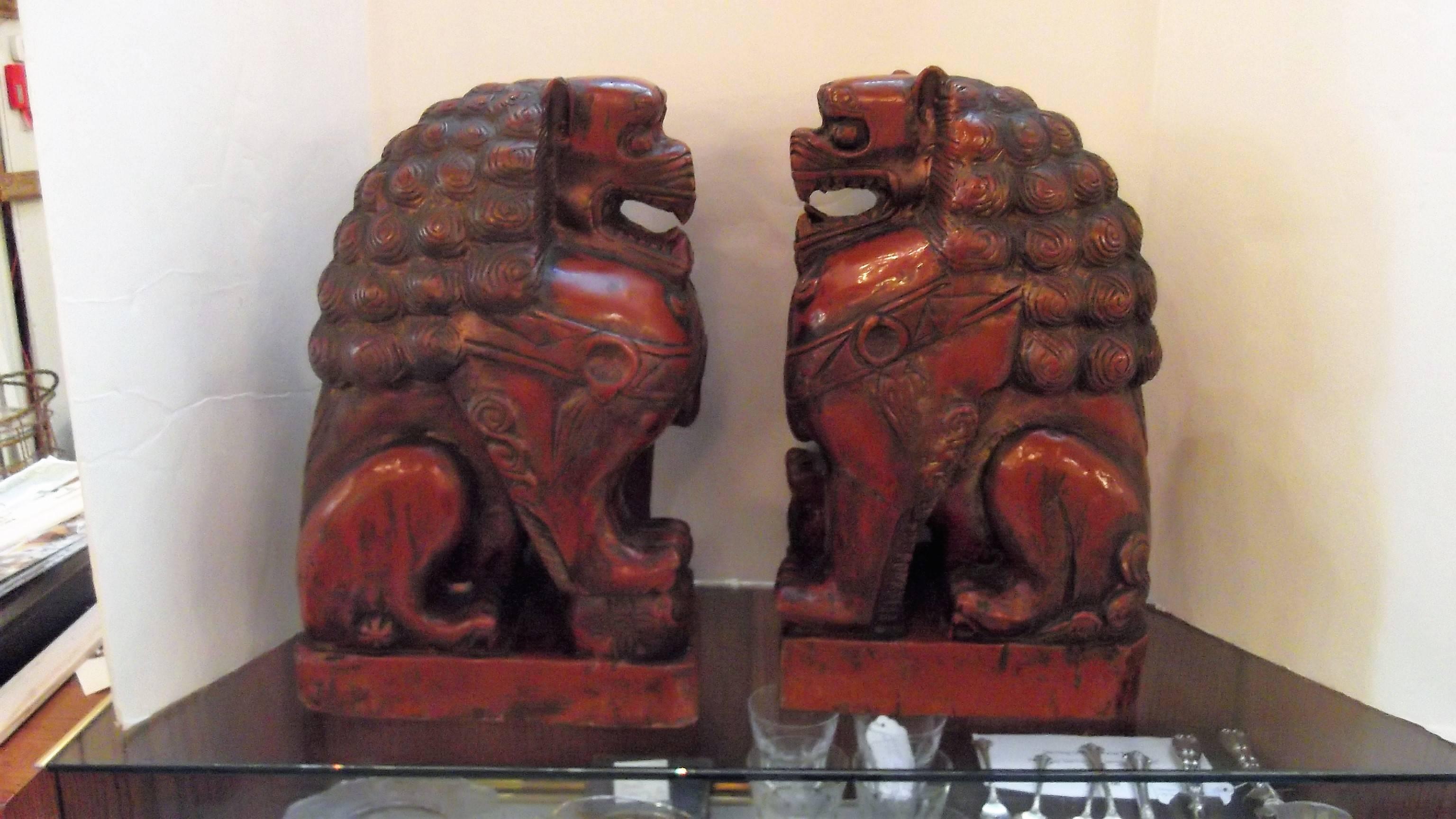 A pair of Lacquered hand-carved food dogs in a cinnabar color. 
Foo dogs are Chinese guardian lions or Imperial guardian lions, traditionally known in Chinese simply as Shi and often called 