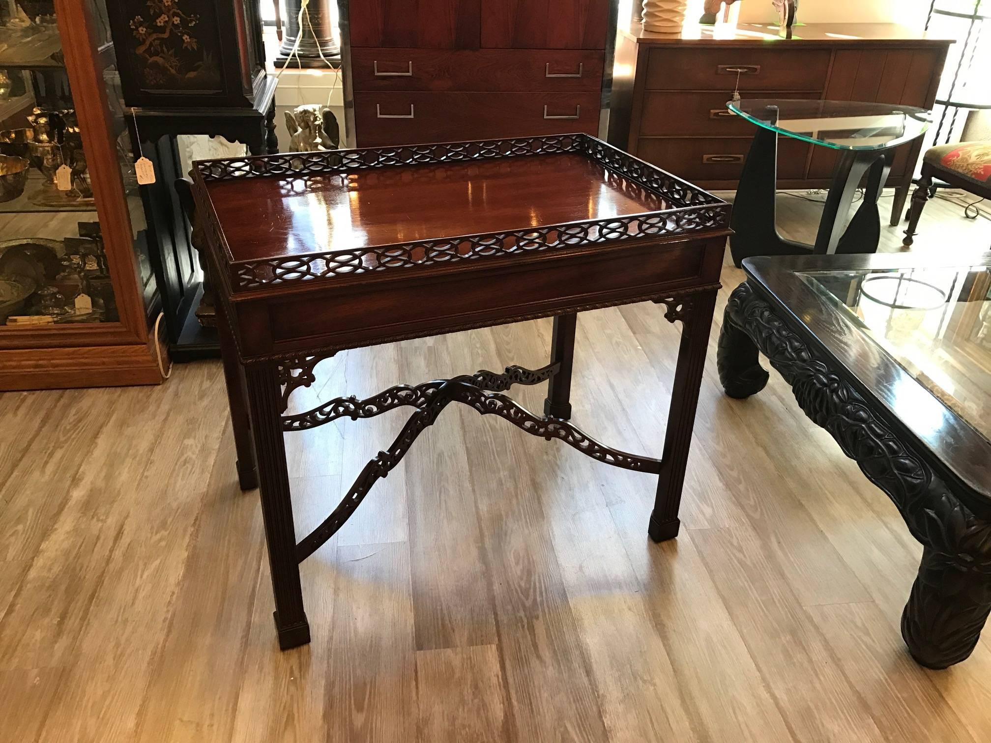 Chippendale tea table, with its Asian inspired design and ornamentation, is made of solid mahogany and figured mahogany veneers. The tea table has delicate pierced wood in the fretwork of the gallery and cross stretchers. A molded skirt with applied