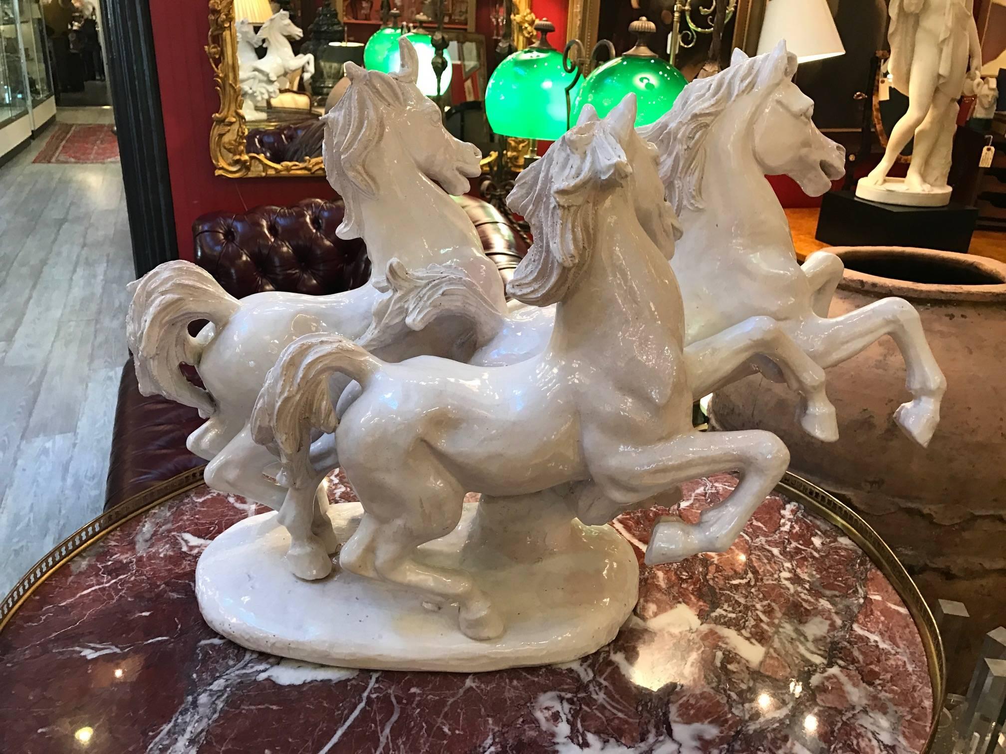 Mid-20th century white glazed pottery sculpture of three running stallions. This Italian made sculpture is a tin glazes earthenware know as Faience and is signed Italy on underside.