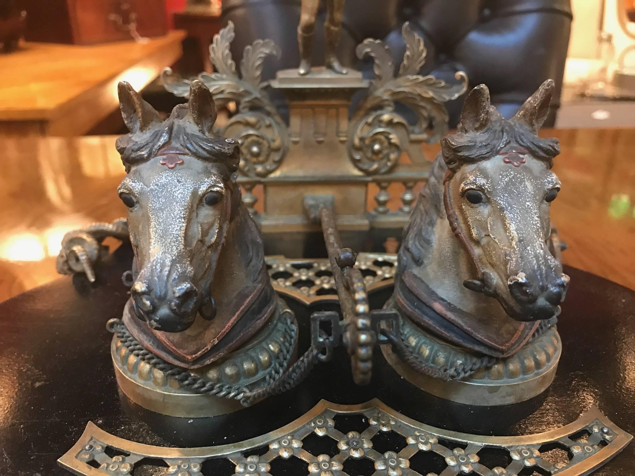 An equestrian themed bronze and wood double inkstand. The footed base supporting the oval black base fitted with two horse head Vienna bronze style inkwells. The back has a figure of a jockey that has a slight lean inward. The back has a place to