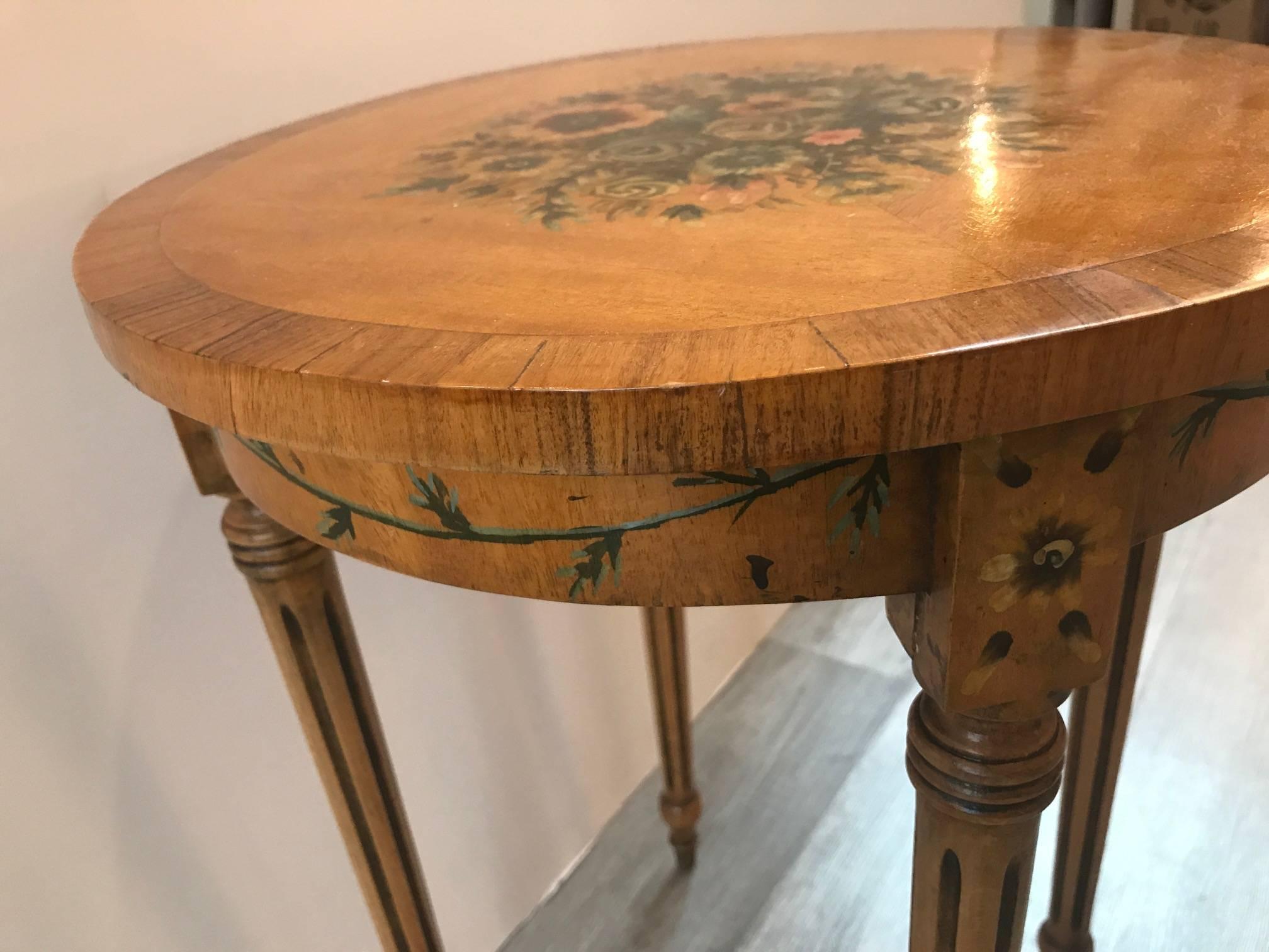 An English Adam style satinwood round drinks table. The hand-painted floral decoration on the top and around the apron with banded edge. Diminutive size, 15 inches diameter, 20 inches tall.