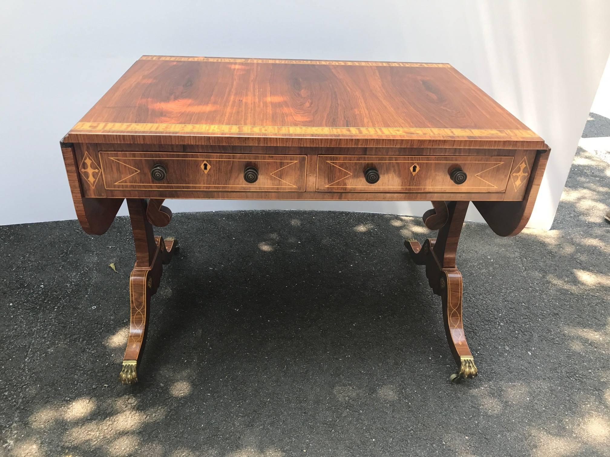 Graceful and elegant rosewood and satinwood inlaid drop leaf console desk. Extraordinary craftsmanship and cabinet maker made in the English Regency style. The figured wood grain with satinwood banding on the top and intertwining pencil inlay on the