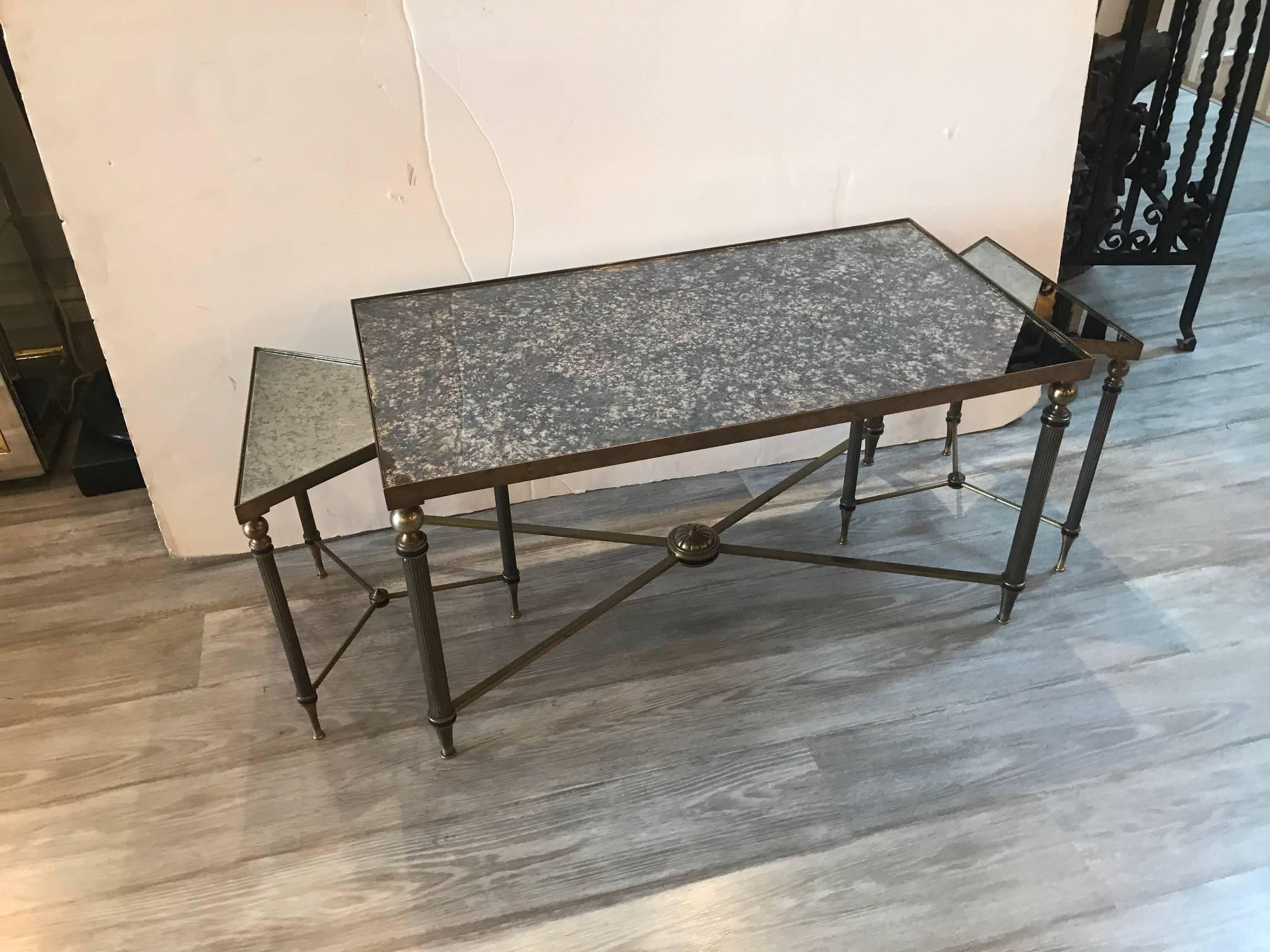 Chic three section distressed mirrored top cocktail table. The larger center rectangle table with two triangular tables that nest into each end. The legs with ribbed lines tapering down to the feet. The mirrors are all original. The rectangular