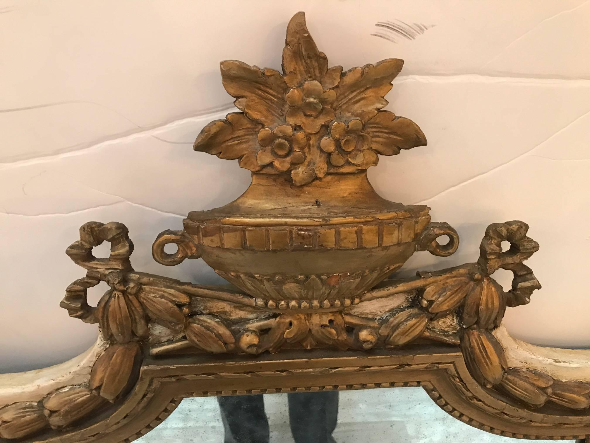 A pair of painted and parcel-gilt Directoire style mirrors. The floral and urn top with swags of leaves with gilt beaded frames. The background is a cream white. The mirrors silvering showing all-over fading as expected.