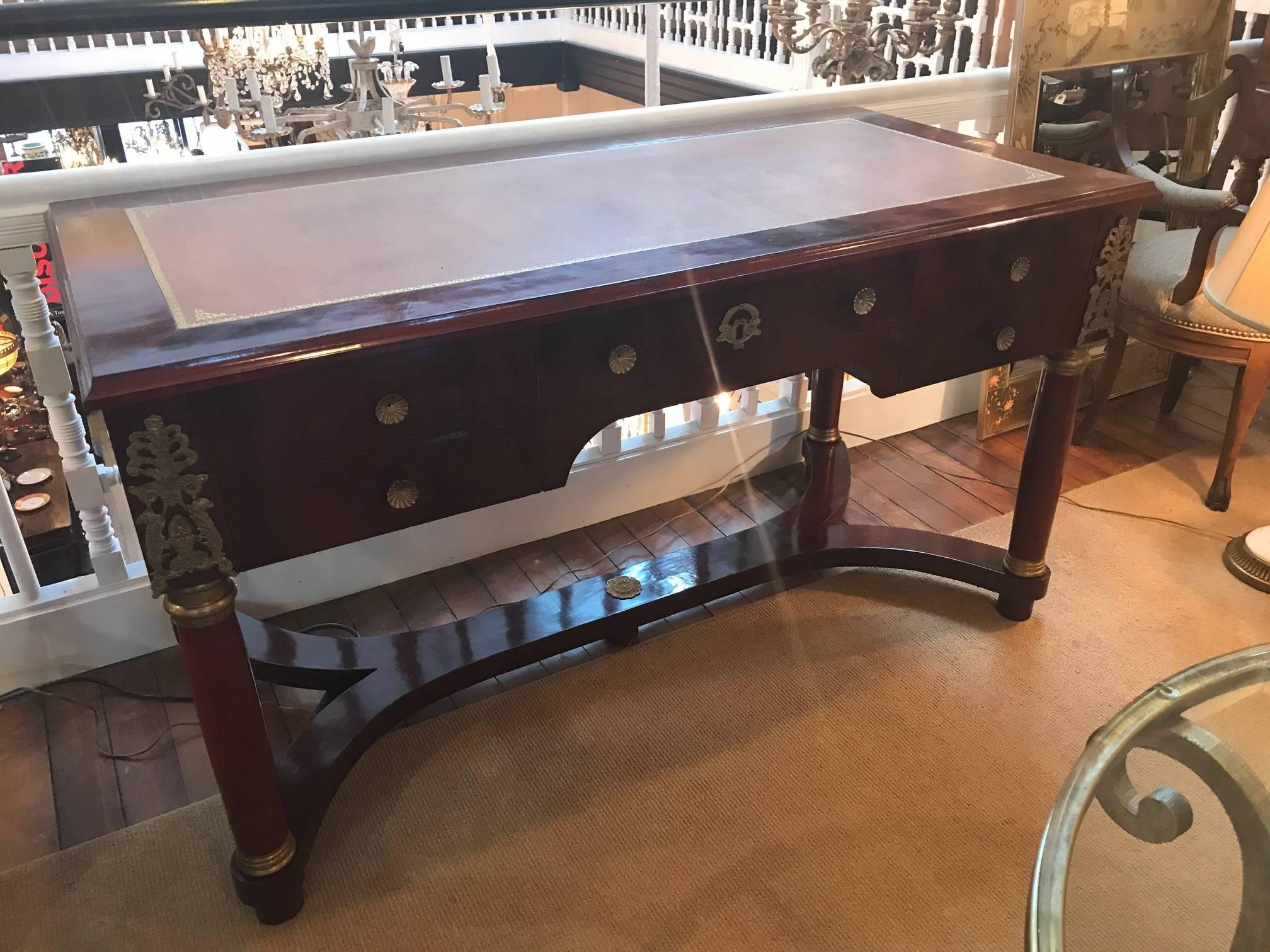 A large mahogany leather topped desk with ormolu mounts. The center drawer, flanked by 2 drawers on each side. The four column style legs with shapely and sturdy stretcher base. Some gilt wear to ormolu. The leather is in excellent condition with