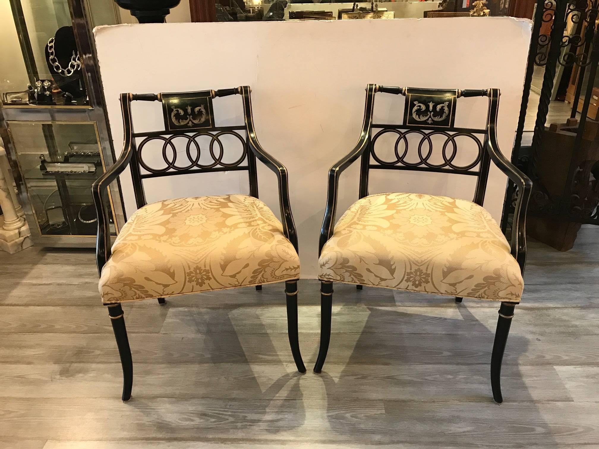 A pair of black Regency style armchairs made by the Baker Furniture Company. These chairs are a Baker Classic, these being a much earlier version with the hand-painted backs. The newly covered seats in a timeless soft gold damask.
The original set